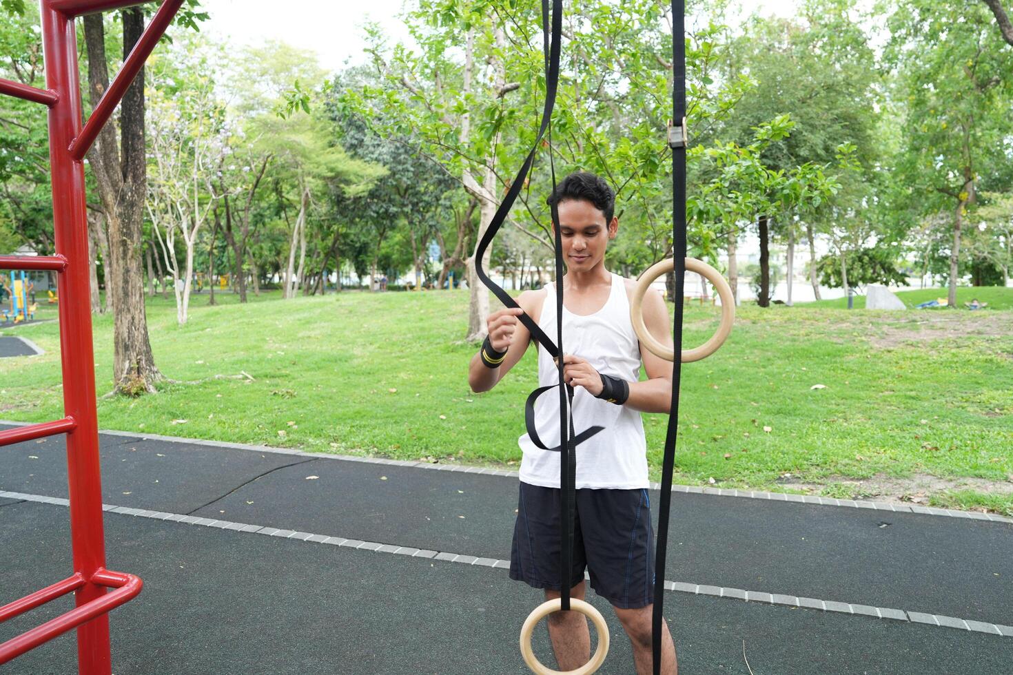 Asian man practicing gymnastics doing gymnastics bar and hoop exercises and stretching and resting for sports. photo