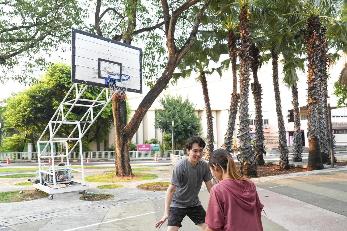 The male and female basketball players practice using the ball in the park court diligently and happily. photo