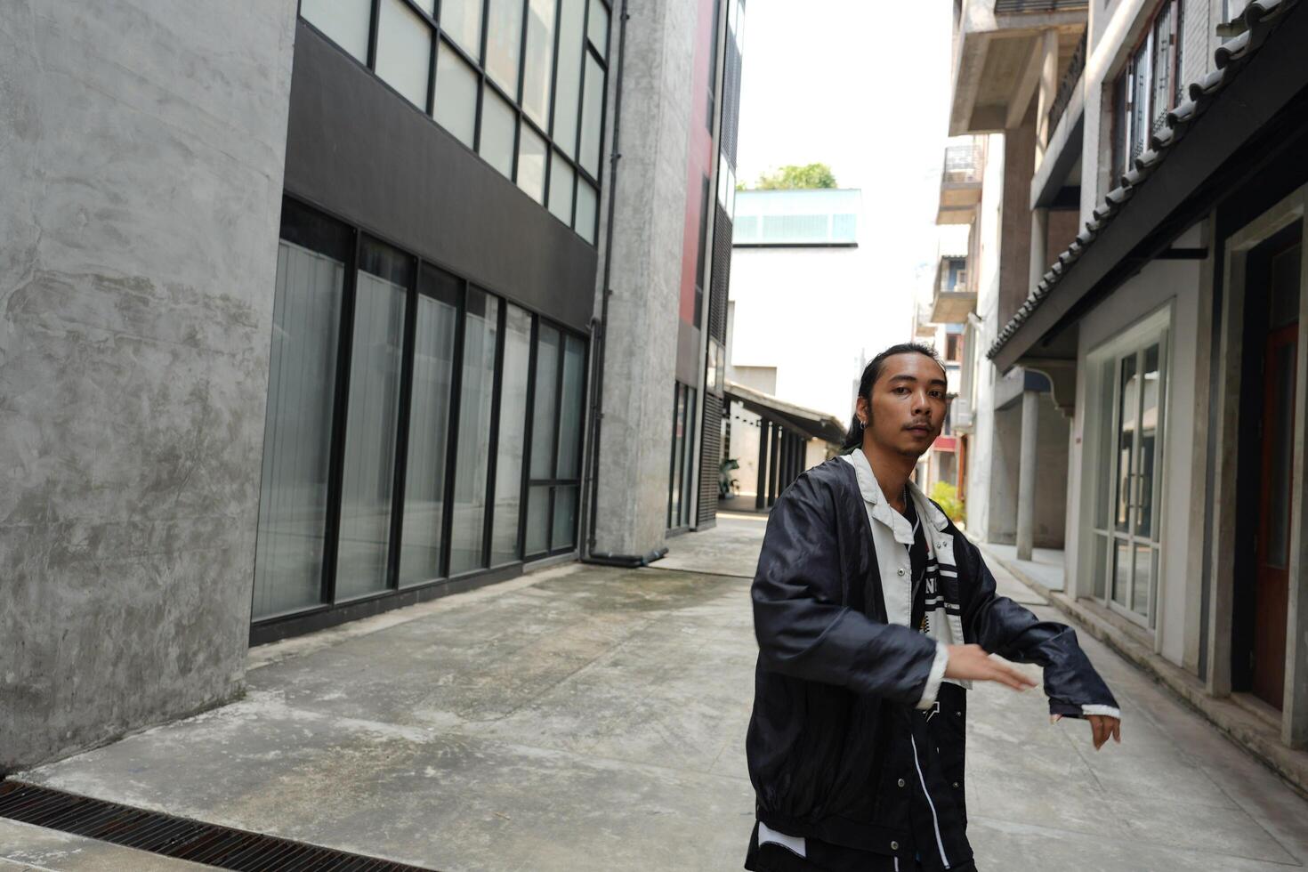 ASian man is dancing in hip hop style at outdoor space. Professional solo dancer is performing in public area. photo