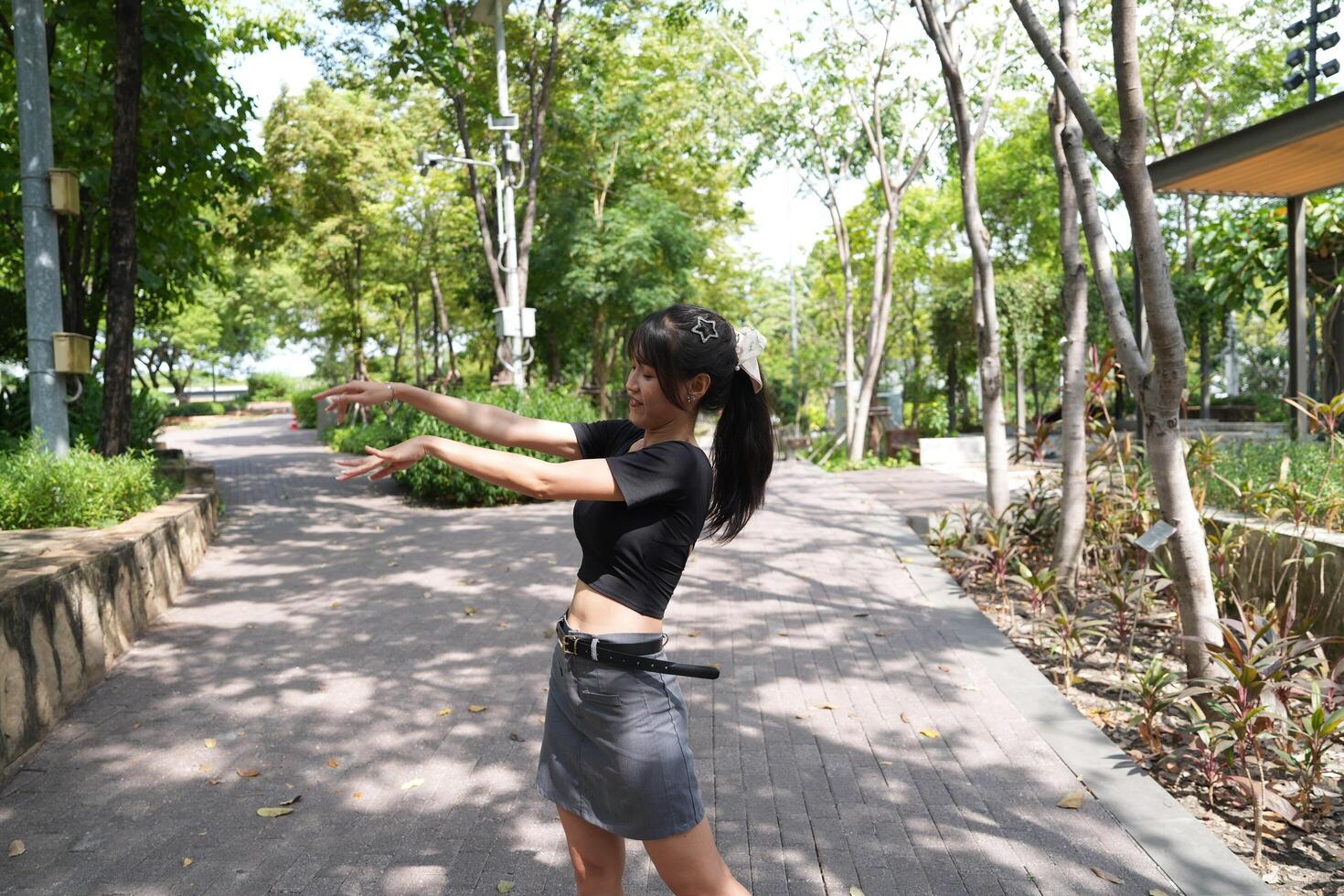 Asian woman dancing in the middle of a park photo