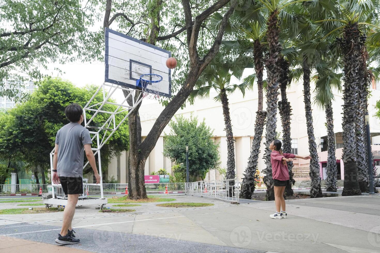 The male and female basketball players practice using the ball in the park court diligently and happily. photo