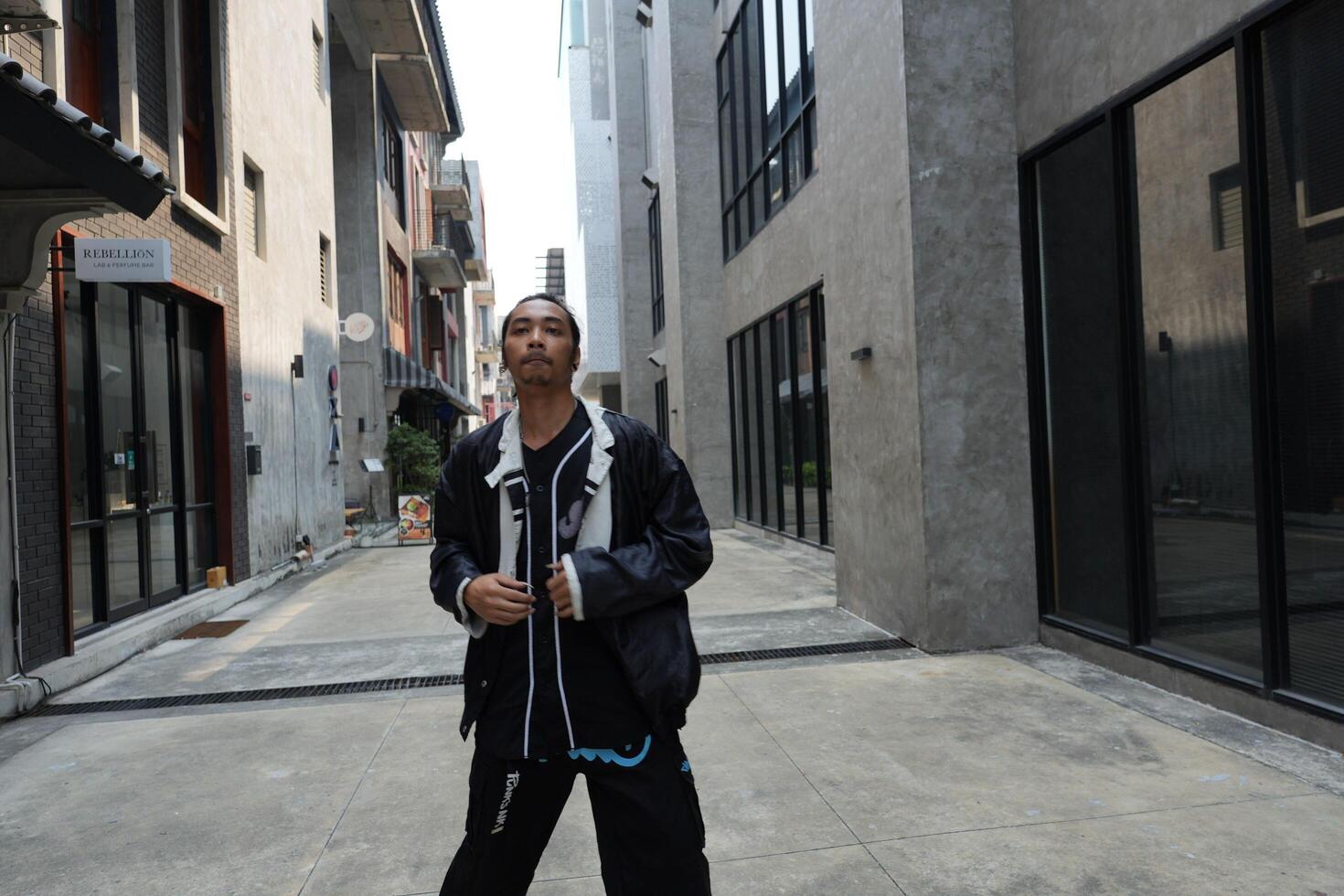 ASian man is dancing in hip hop style at outdoor space. Professional solo dancer is performing in public area. photo