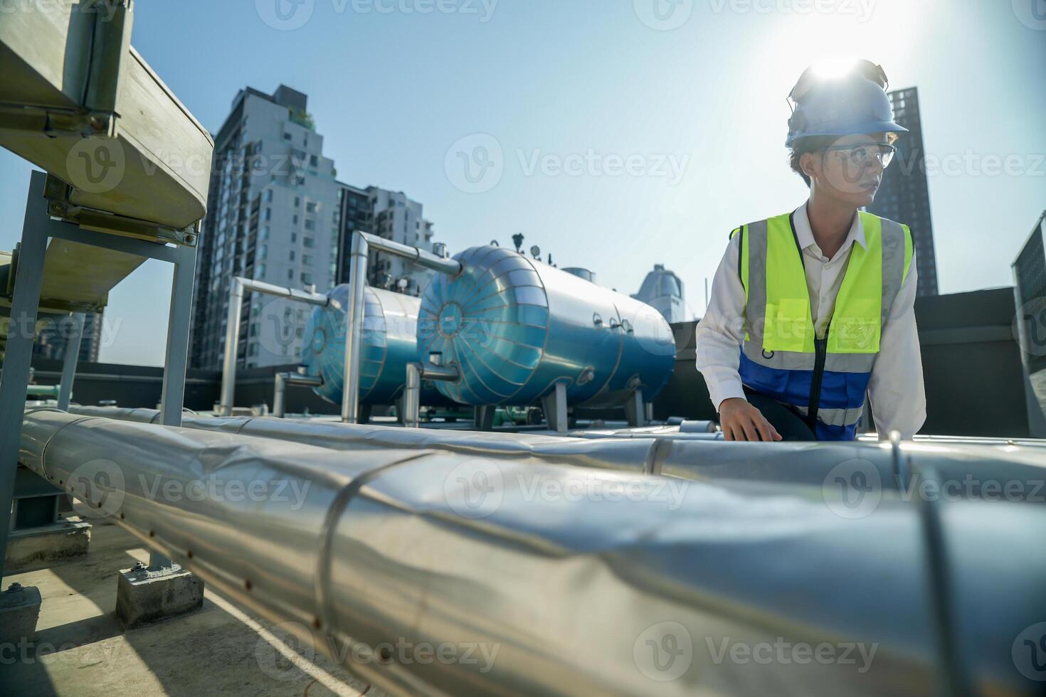 Urban rooftop scene showing a young engineer with a radio, inspecting and adjusting equipment in a sunny city environment. Safety and precision at work. photo