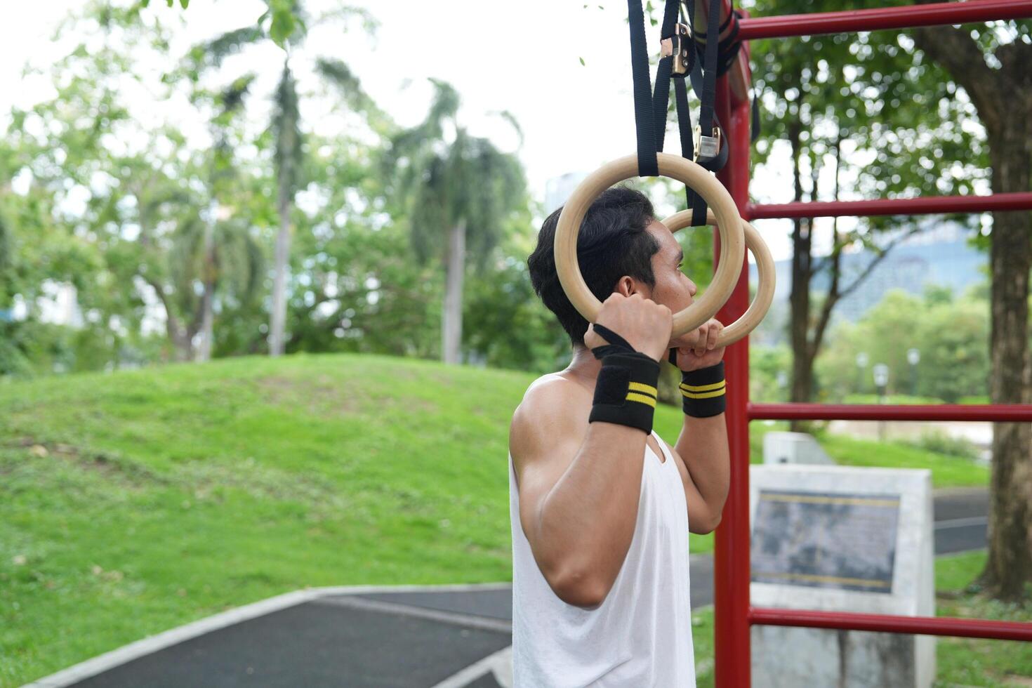 Asian man practicing gymnastics, doing gymnastics bar and hoop exercises and stretching, resting for sports. photo