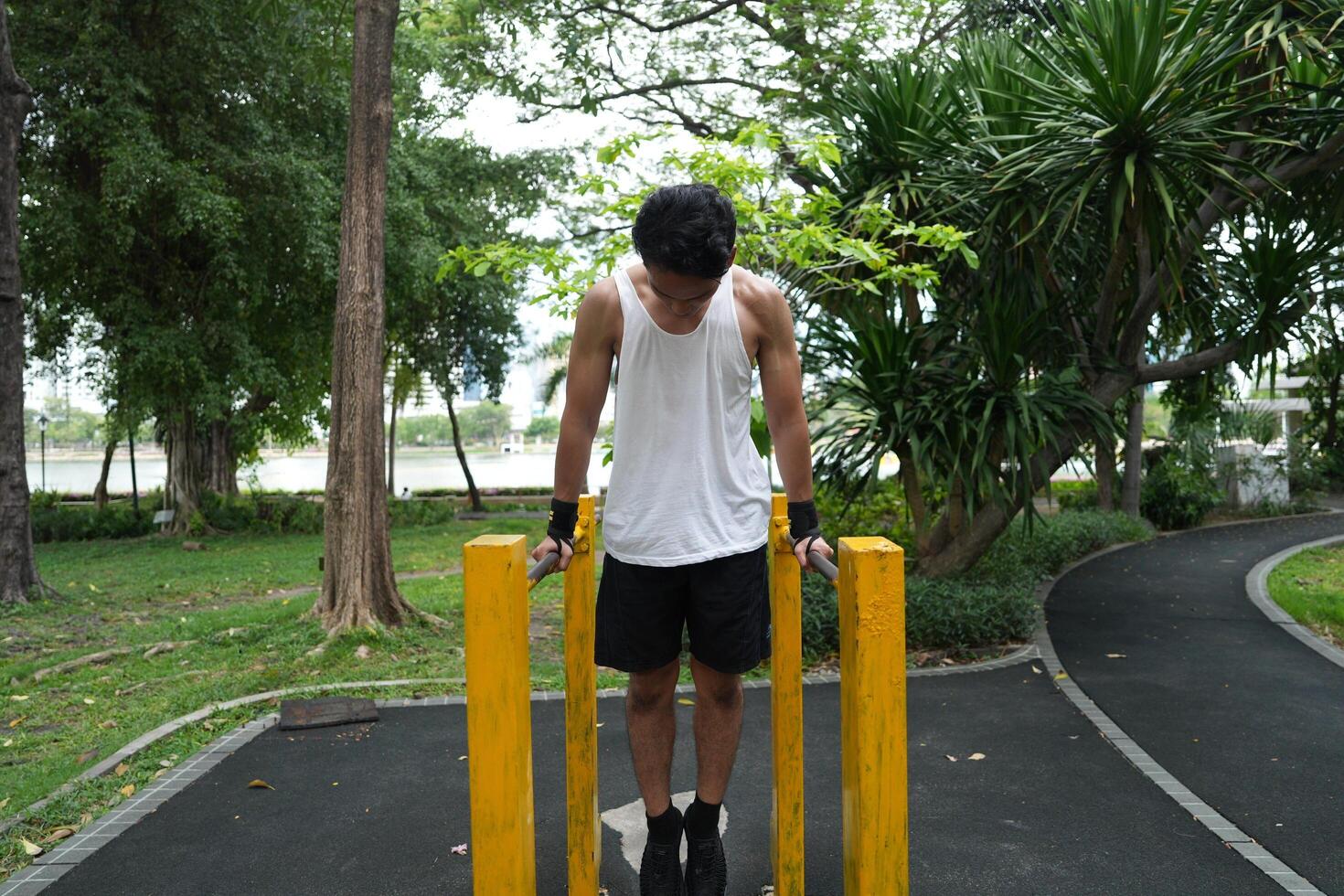 Asian man practicing gymnastics, doing gymnastics bar and hoop exercises and stretching, resting for sports. photo