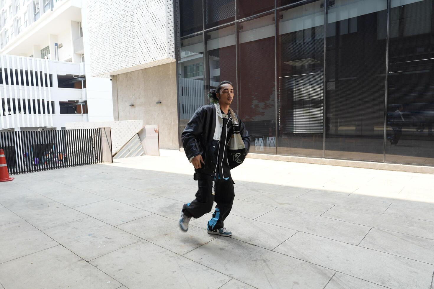 ASian man is dancing in hip hop style at outdoor space. Professional solo dancer is performing in public area. photo