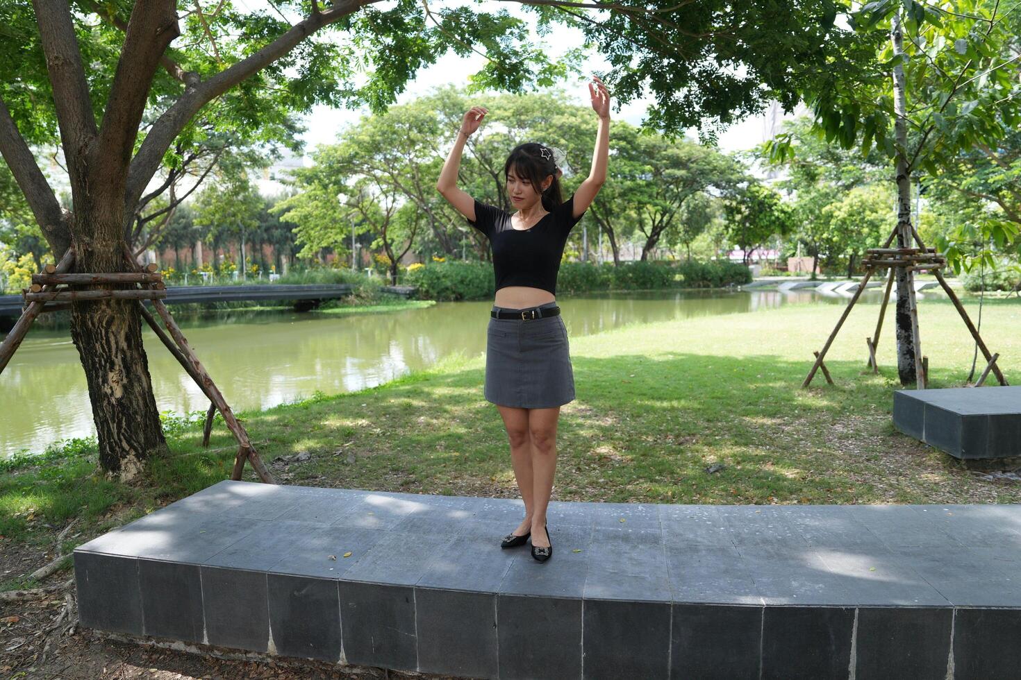 Asian woman dancing in the middle of a park photo