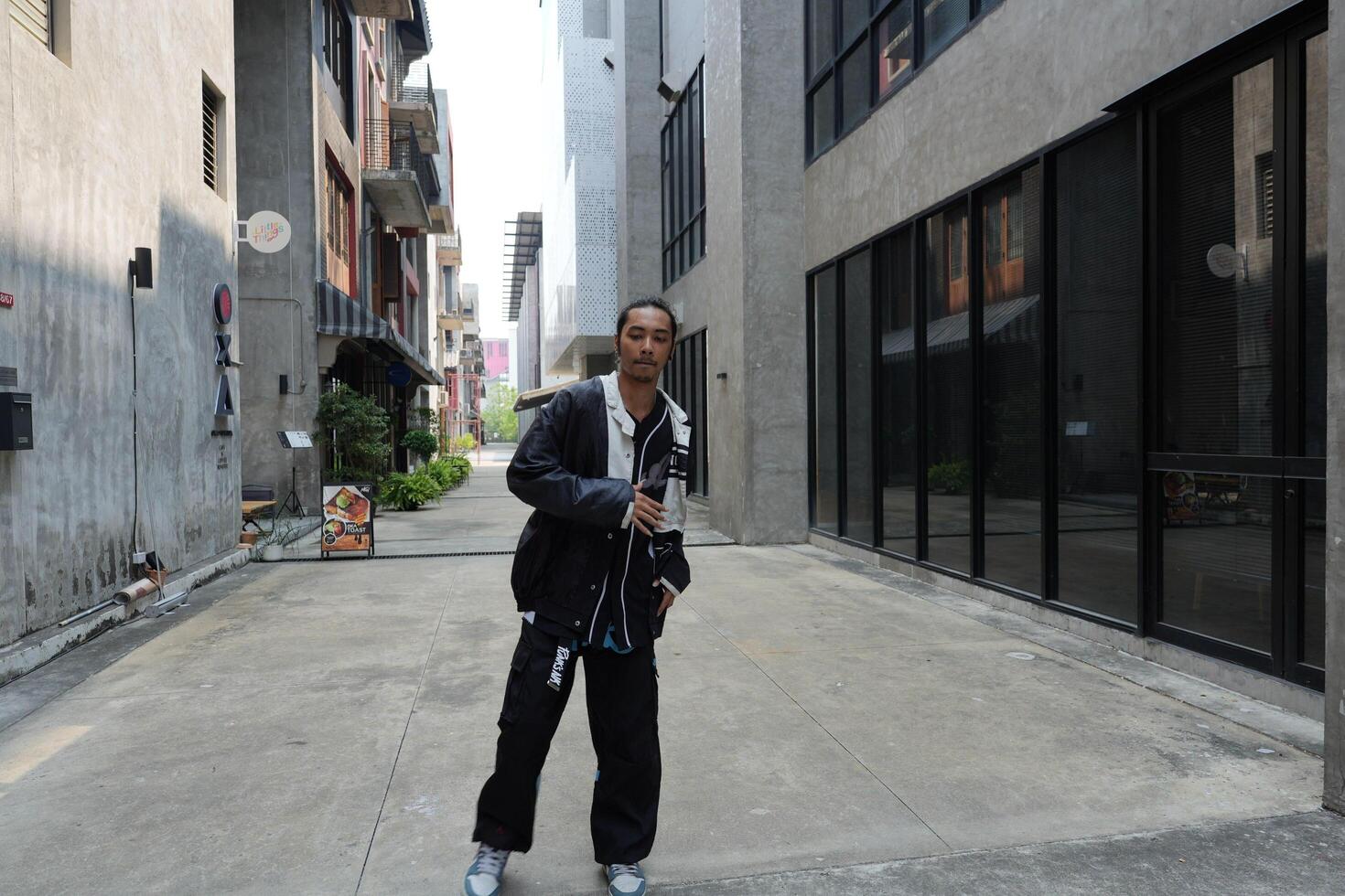 ASian man is dancing in hip hop style at outdoor space. Professional solo dancer is performing in public area. photo