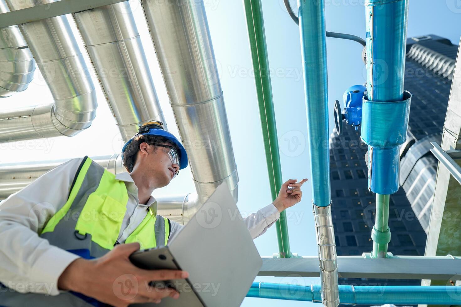 Industrial engineer adjusting pipeline valve with radio communication on construction site. Engineer on urban construction site using radio to coordinate with team on a sunny industrial rooftop. photo