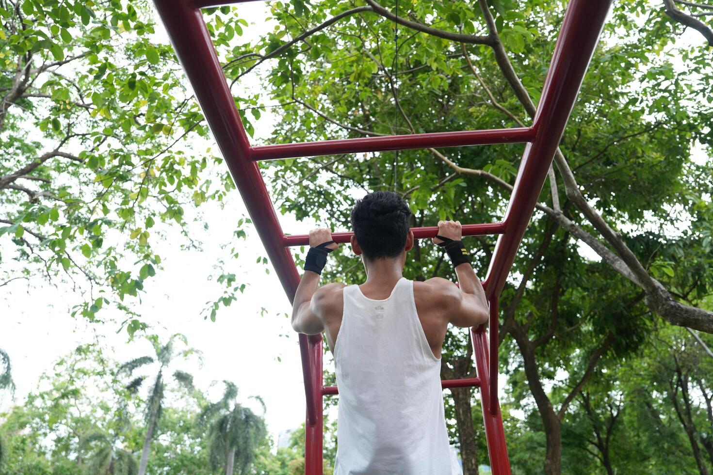 Asian man practicing gymnastics, doing gymnastics bar and hoop exercises and stretching, resting for sports. photo