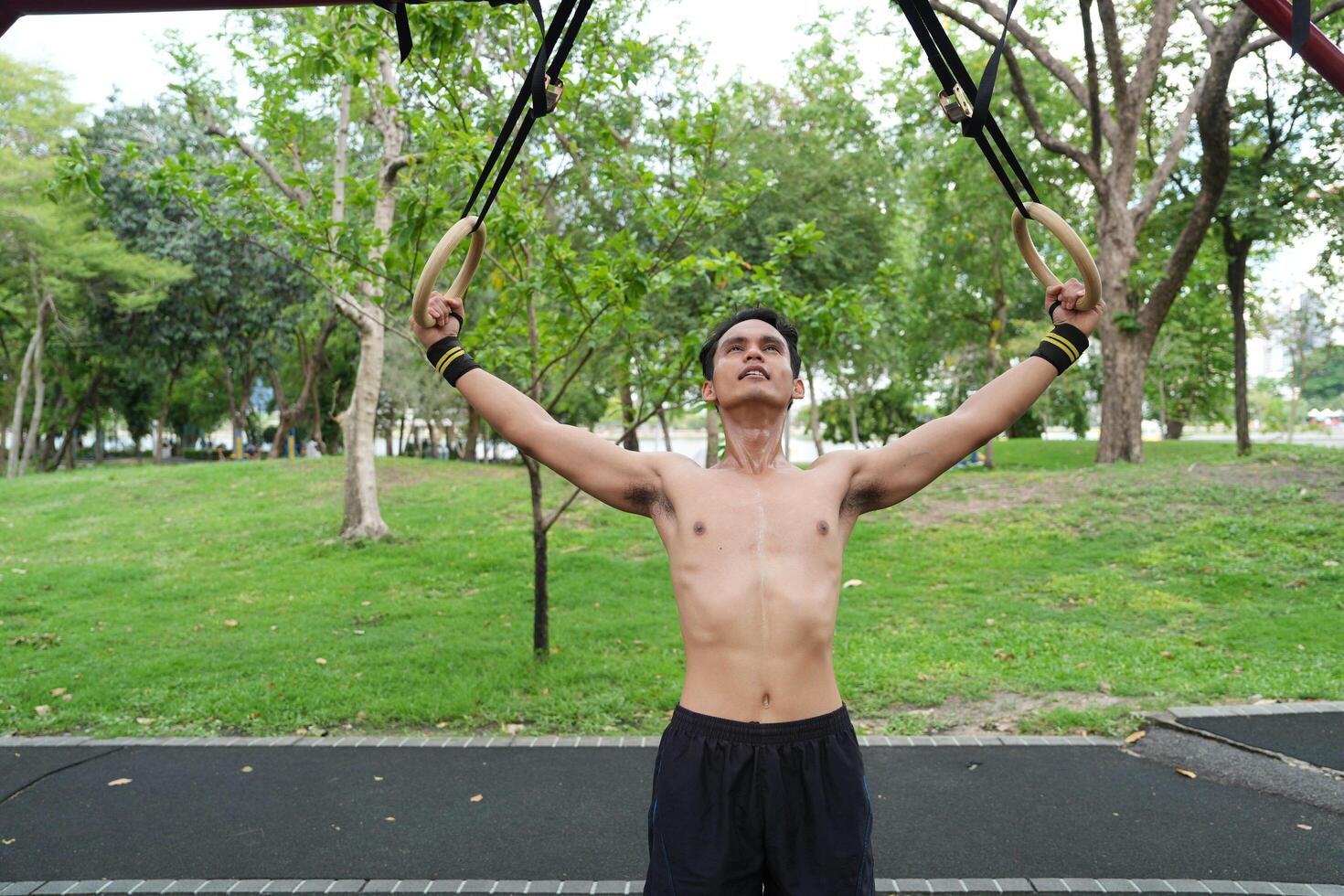 Asian man practicing gymnastics, doing gymnastics bar and hoop exercises and stretching, resting for sports. photo