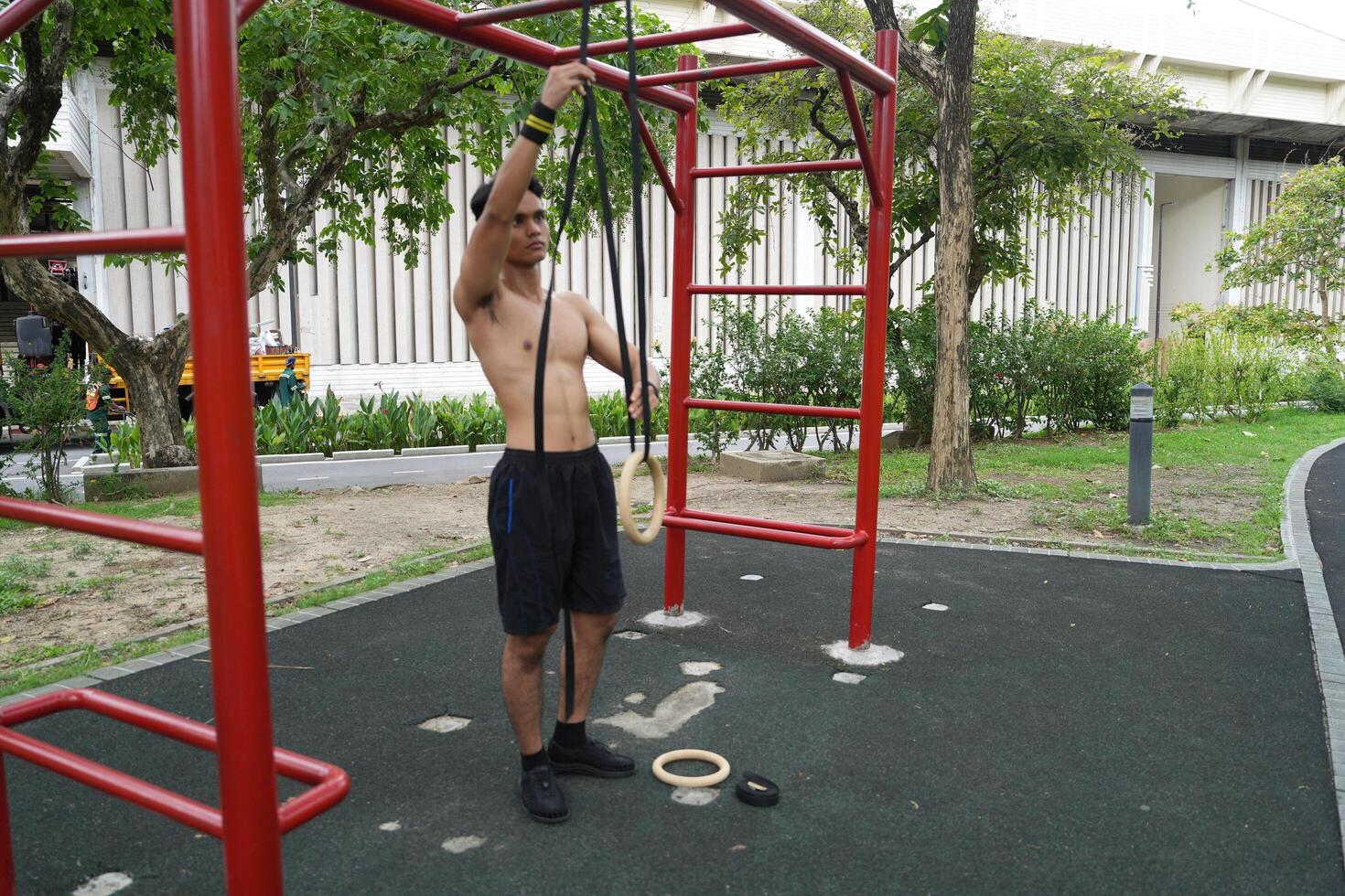 Asian man practicing gymnastics, doing gymnastics bar and hoop exercises and stretching, resting for sports. photo