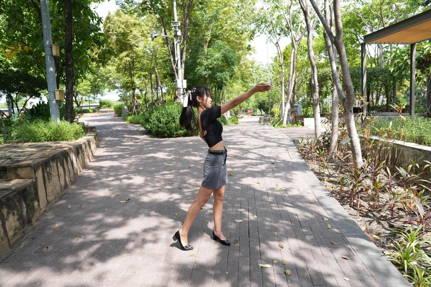 Asian woman dancing in the middle of a park photo