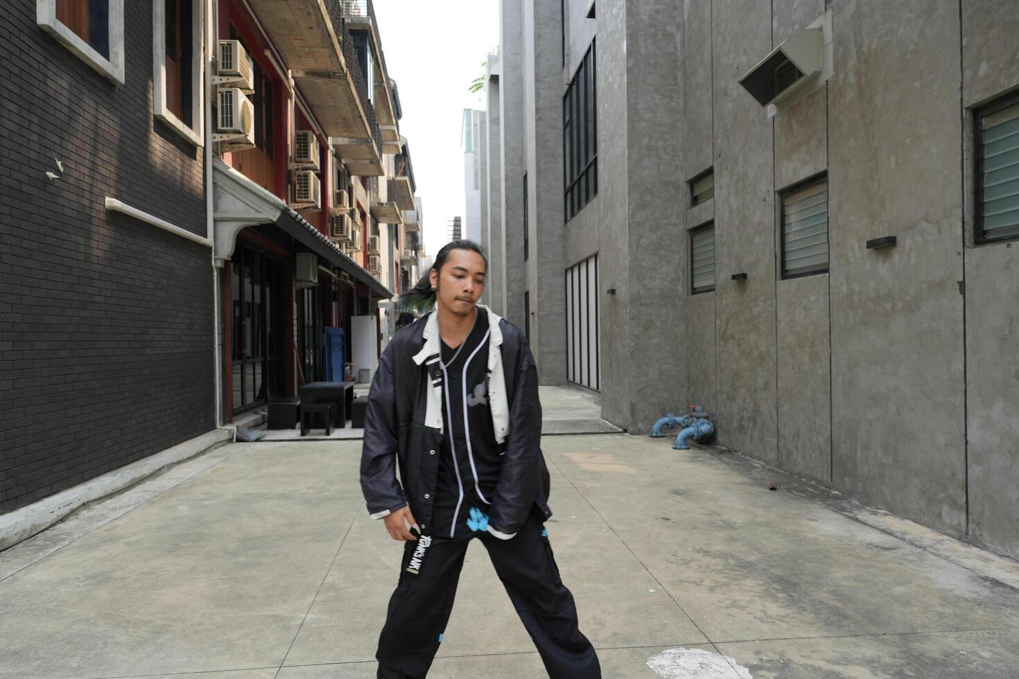 ASian man is dancing in hip hop style at outdoor space. Professional solo dancer is performing in public area. photo