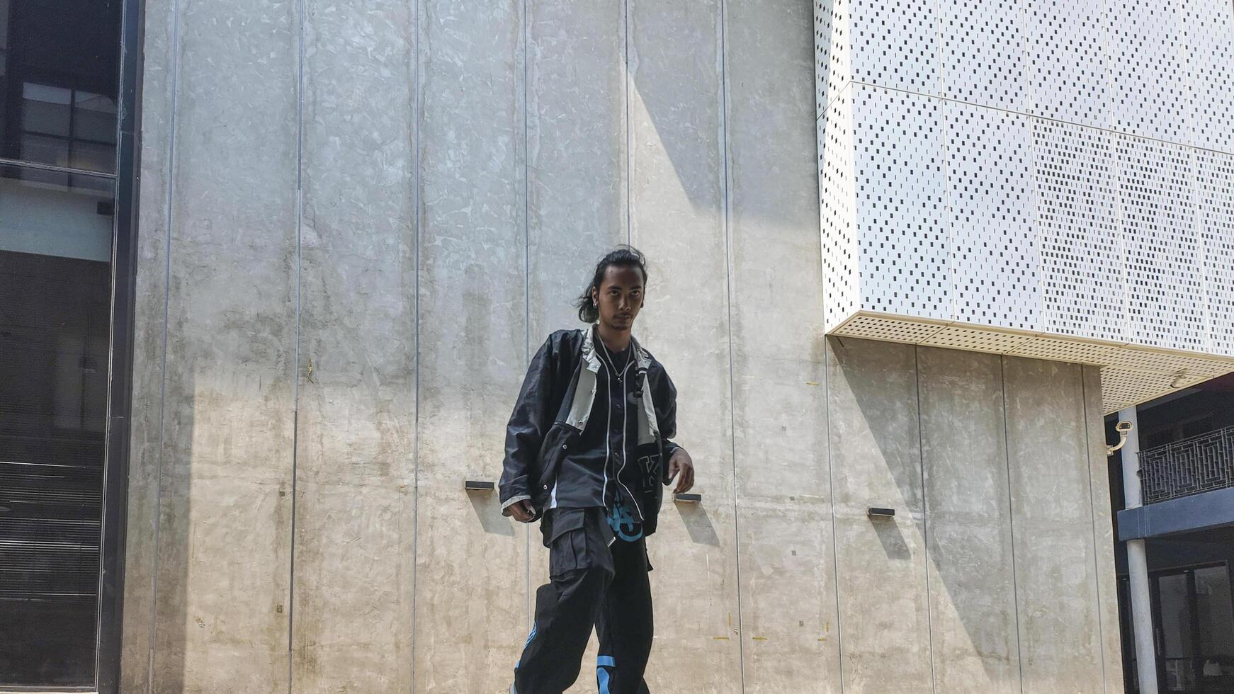 ASian man is dancing in hip hop style at outdoor space. Professional solo dancer is performing in public area. photo