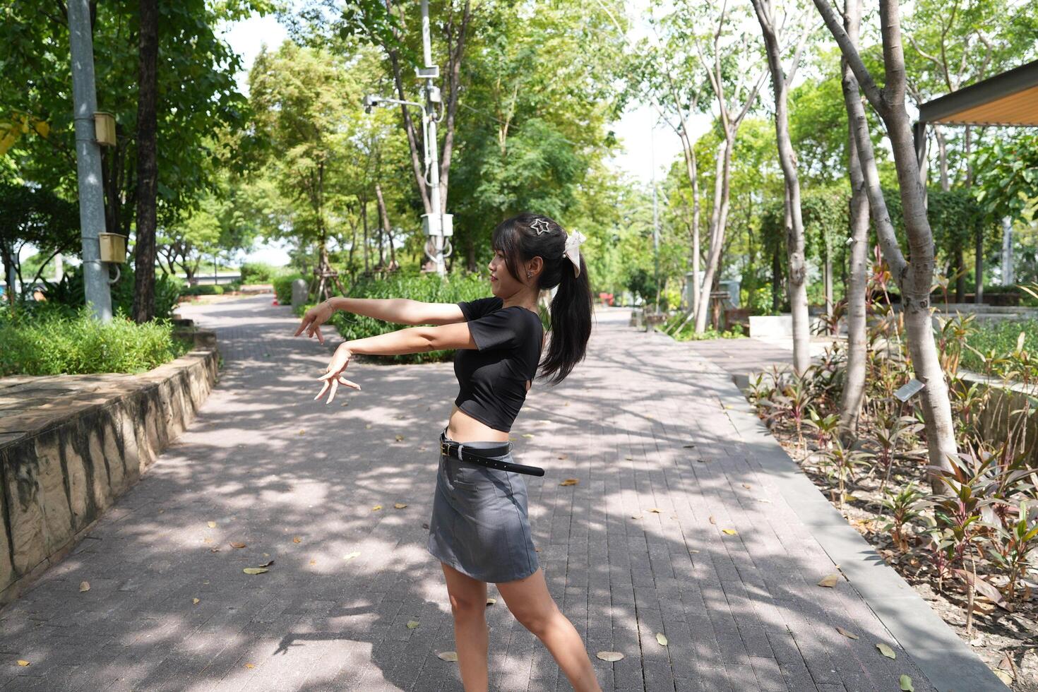 Asian woman dancing in the middle of a park photo