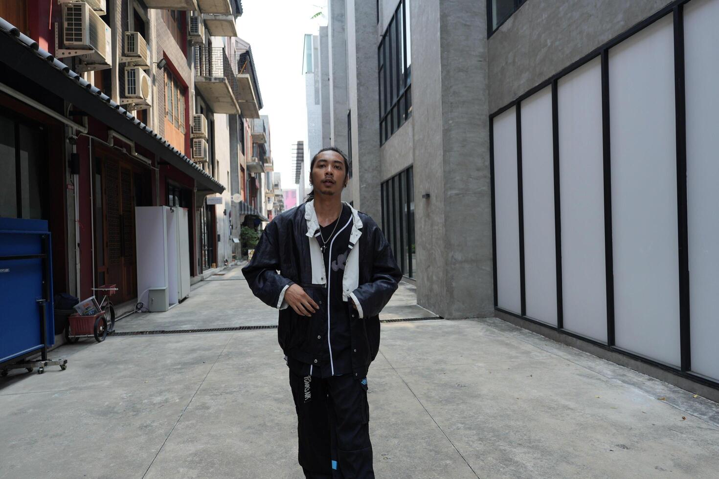ASian man is dancing in hip hop style at outdoor space. Professional solo dancer is performing in public area. photo
