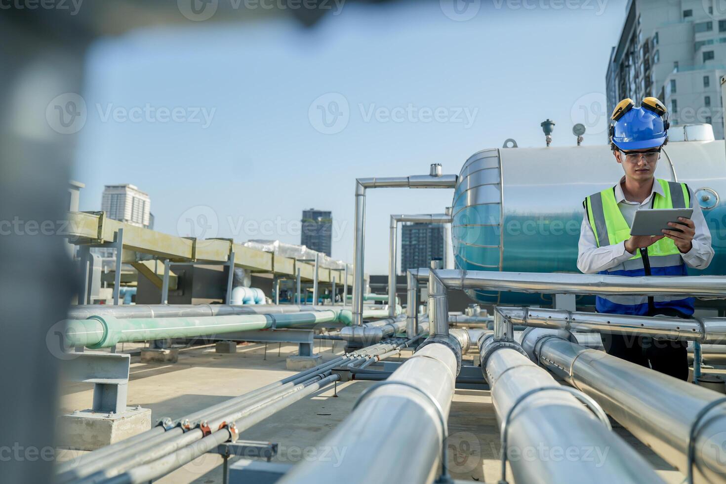 Urban rooftop scene showing a young engineer with a radio, inspecting and adjusting equipment in a sunny city environment. Safety and precision at work. photo