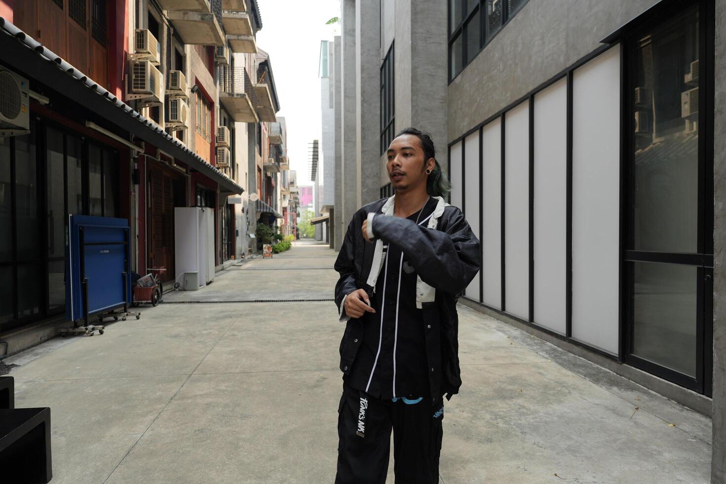 ASian man is dancing in hip hop style at outdoor space. Professional solo dancer is performing in public area. photo