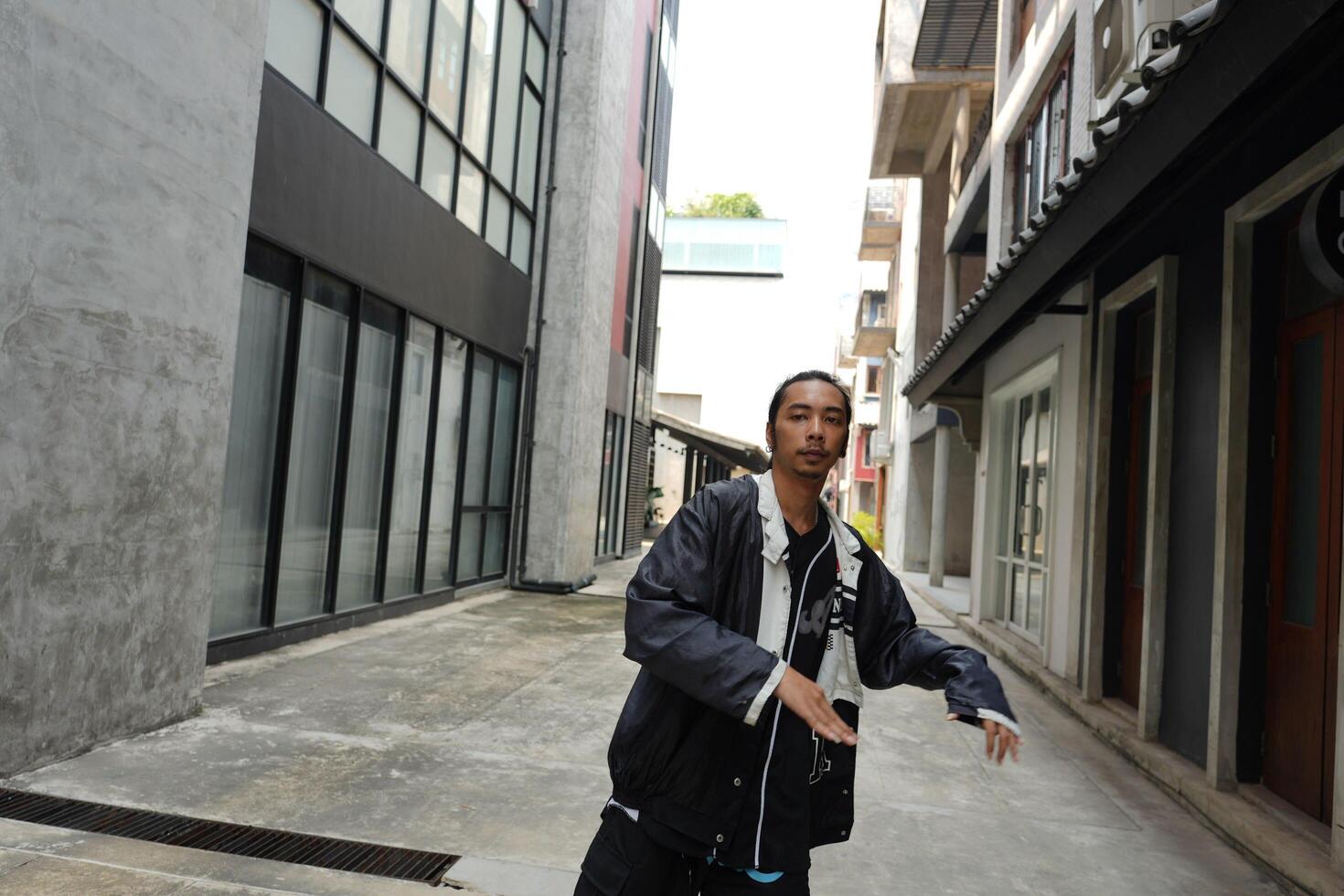 ASian man is dancing in hip hop style at outdoor space. Professional solo dancer is performing in public area. photo