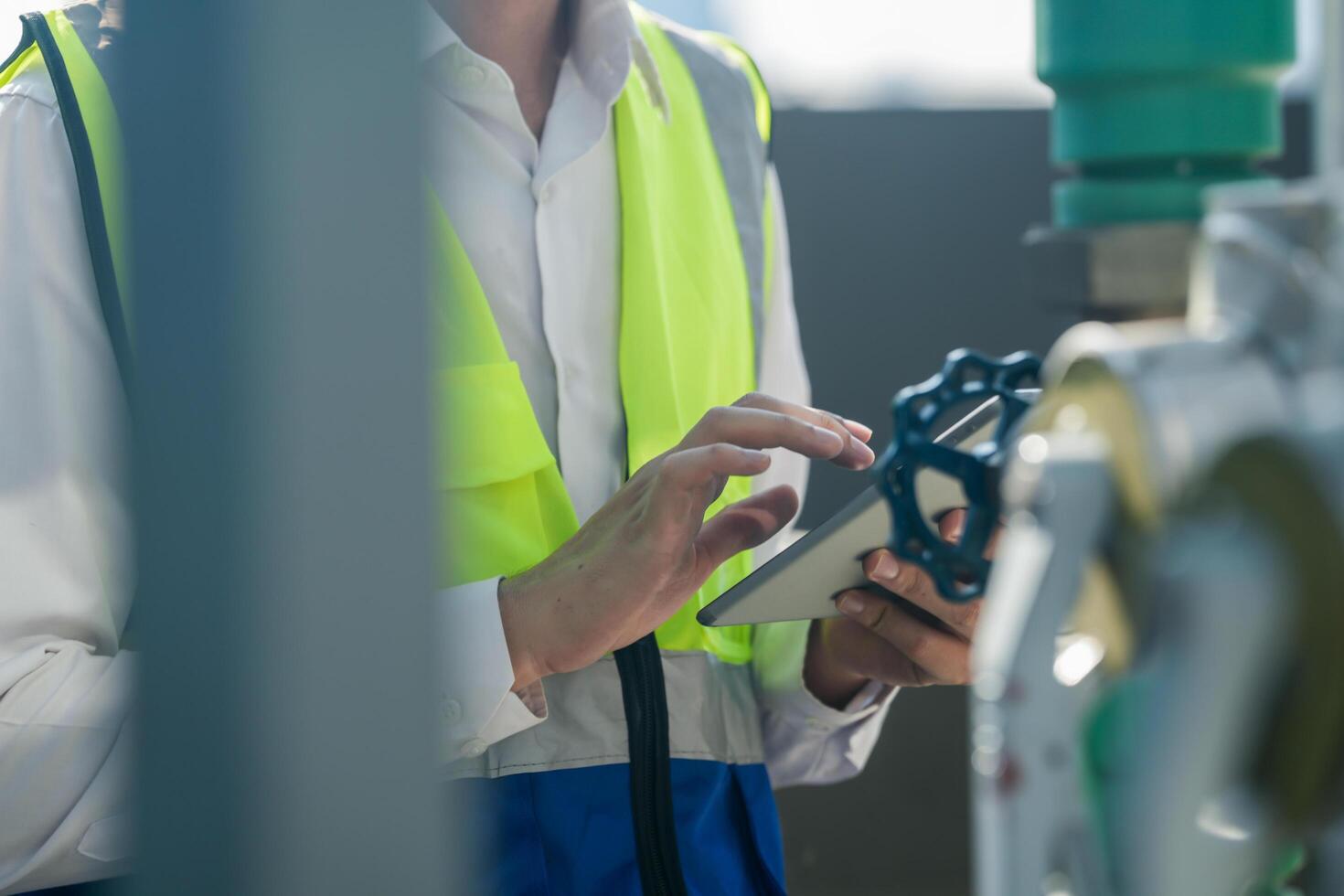 Focused engineer tightening valve with wrench at industrial plant, daylight setting. Technician in safety vest using wrench on industrial piping, clear day backdrop. photo