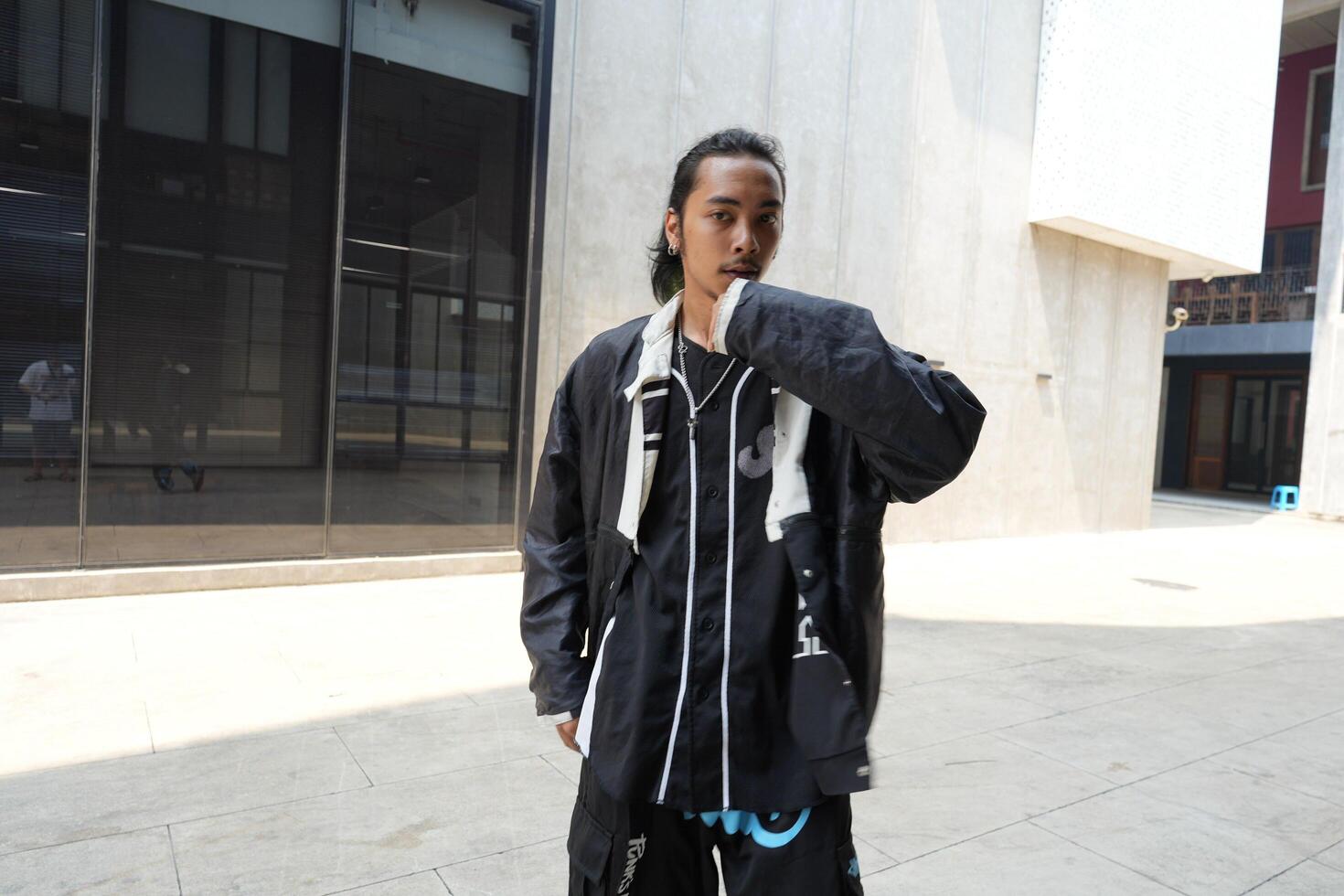 ASian man is dancing in hip hop style at outdoor space. Professional solo dancer is performing in public area. photo