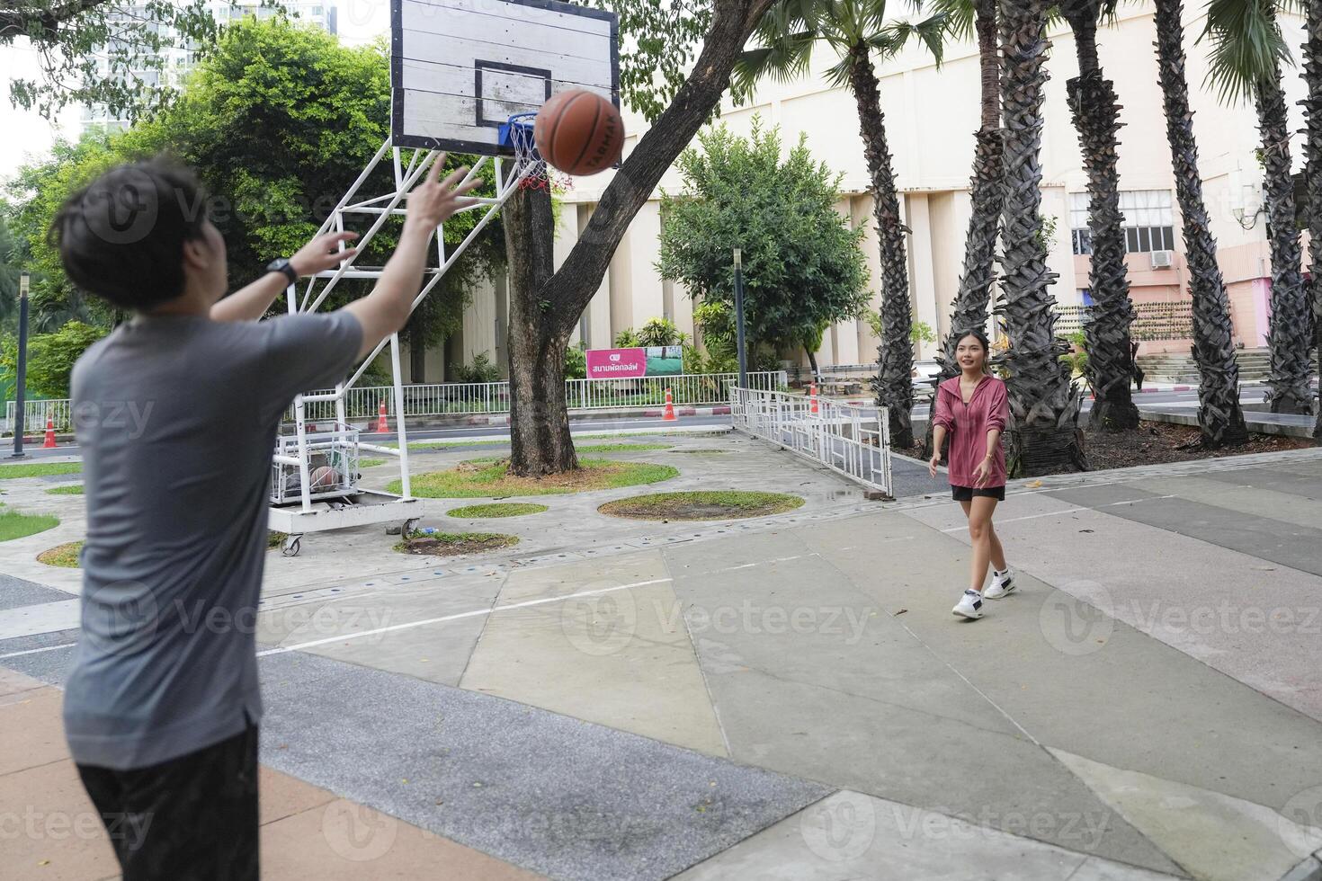 The male and female basketball players practice using the ball in the park court diligently and happily. photo