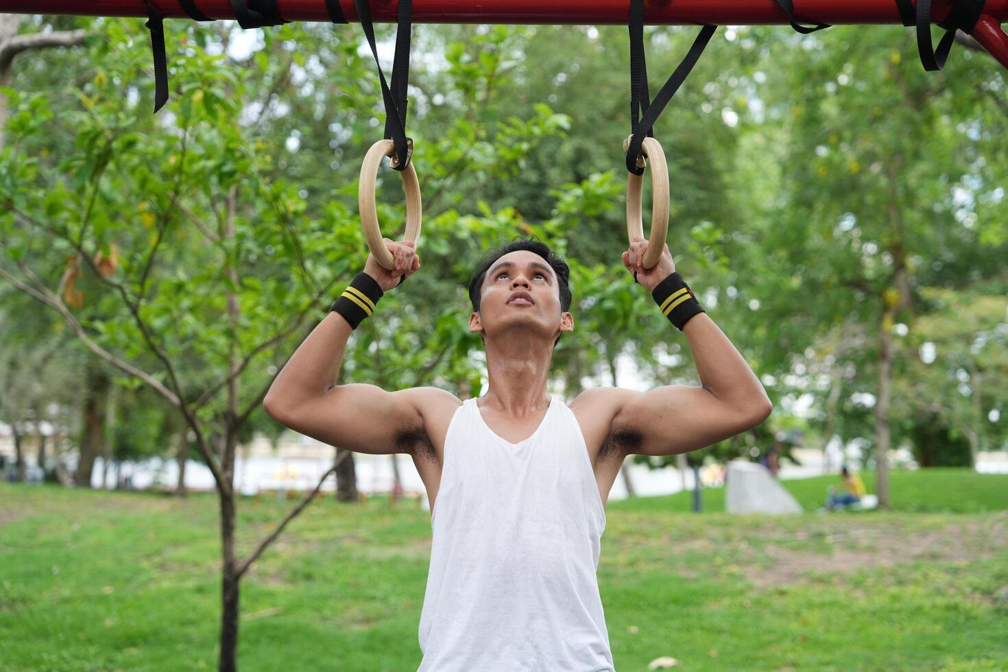 Asian man practicing gymnastics doing gymnastics bar and hoop exercises and stretching and resting for sports. photo