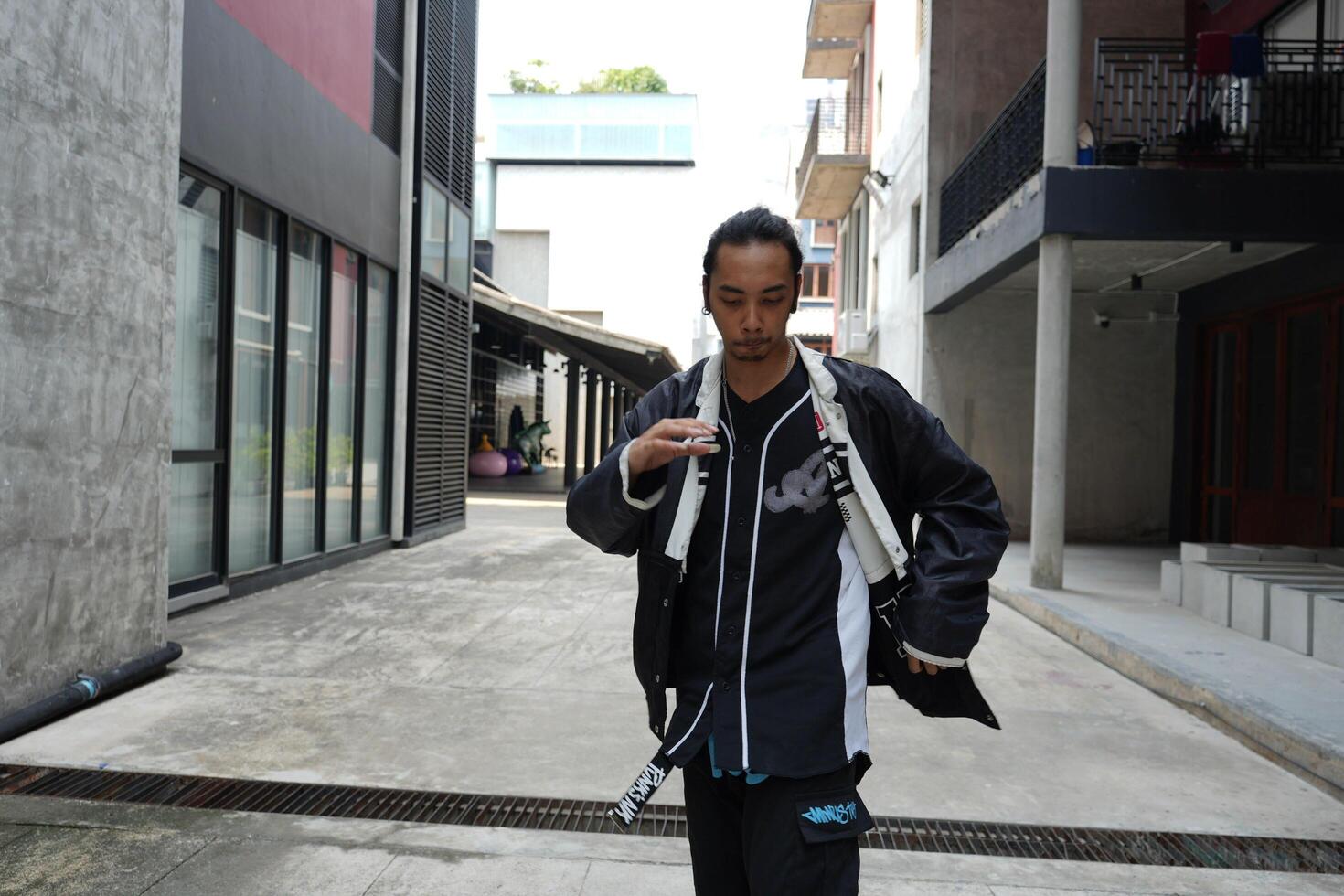 ASian man is dancing in hip hop style at outdoor space. Professional solo dancer is performing in public area. photo