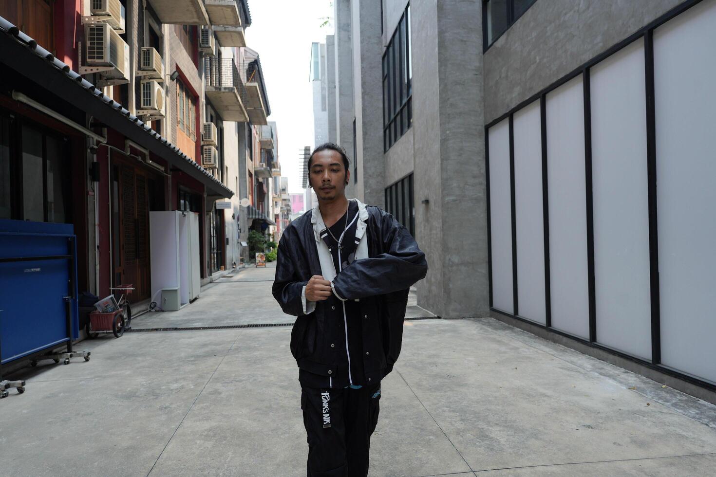 ASian man is dancing in hip hop style at outdoor space. Professional solo dancer is performing in public area. photo
