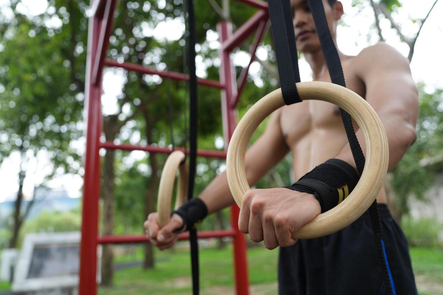 Asian man practicing gymnastics, doing gymnastics bar and hoop exercises and stretching, resting for sports. photo