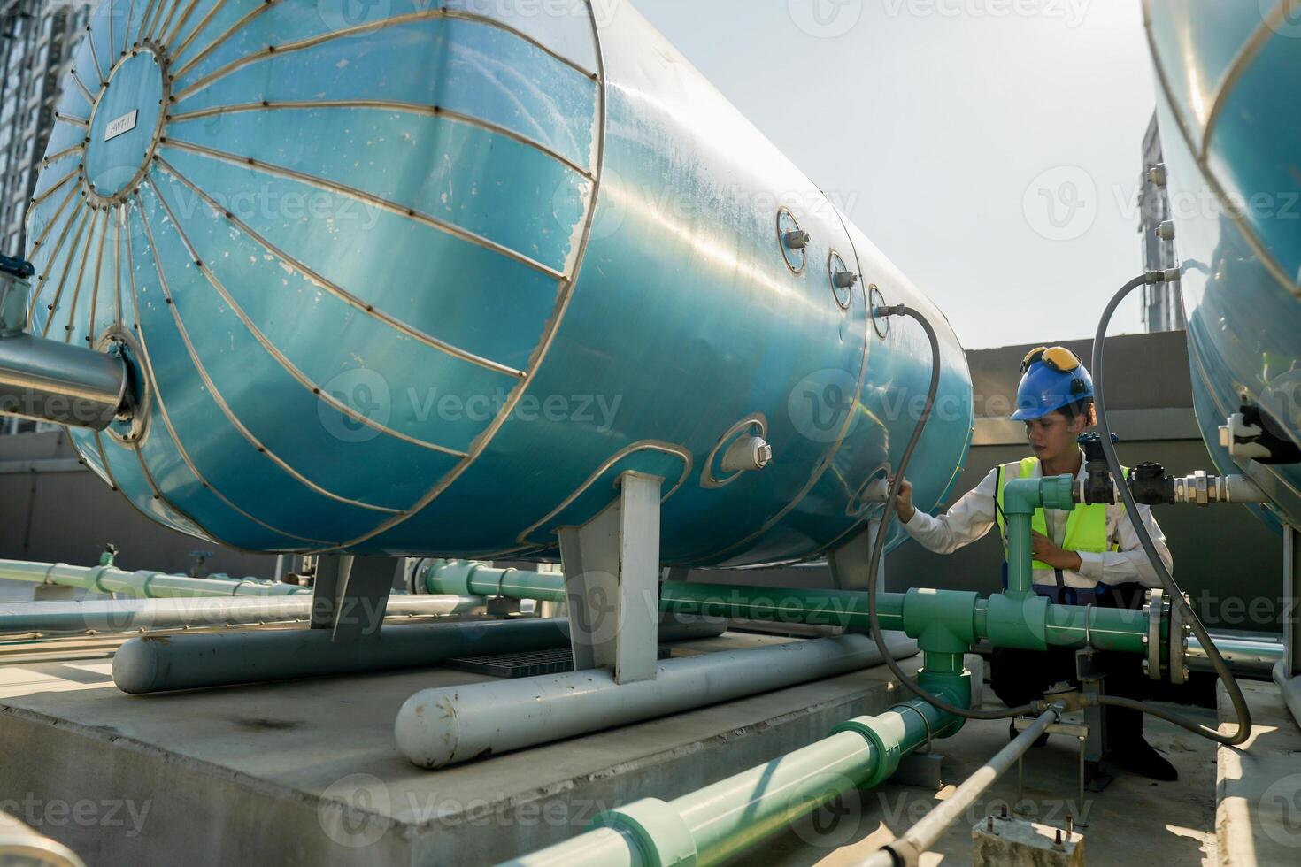 Urban rooftop scene showing a young engineer with a radio, inspecting and adjusting equipment in a sunny city environment. Safety and precision at work. photo