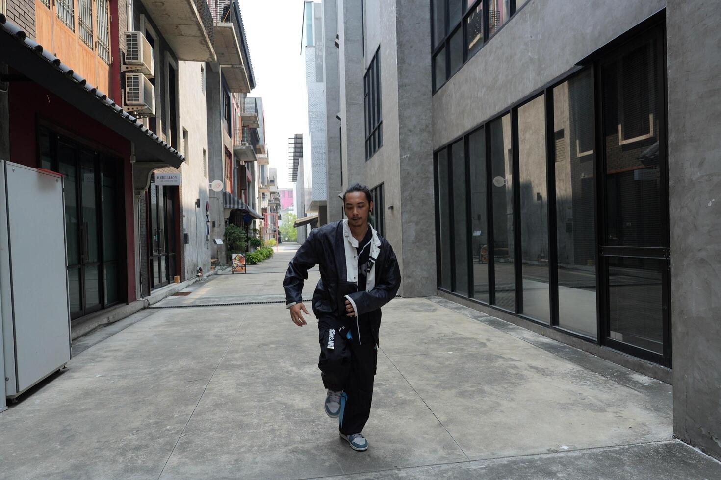 ASian man is dancing in hip hop style at outdoor space. Professional solo dancer is performing in public area. photo