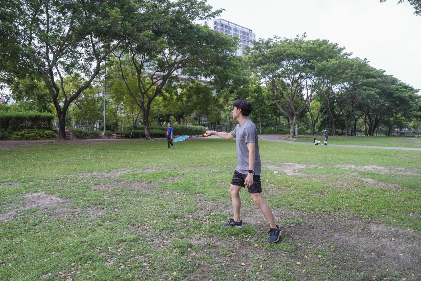 Young people play badminton and repair diligently in the park area. photo