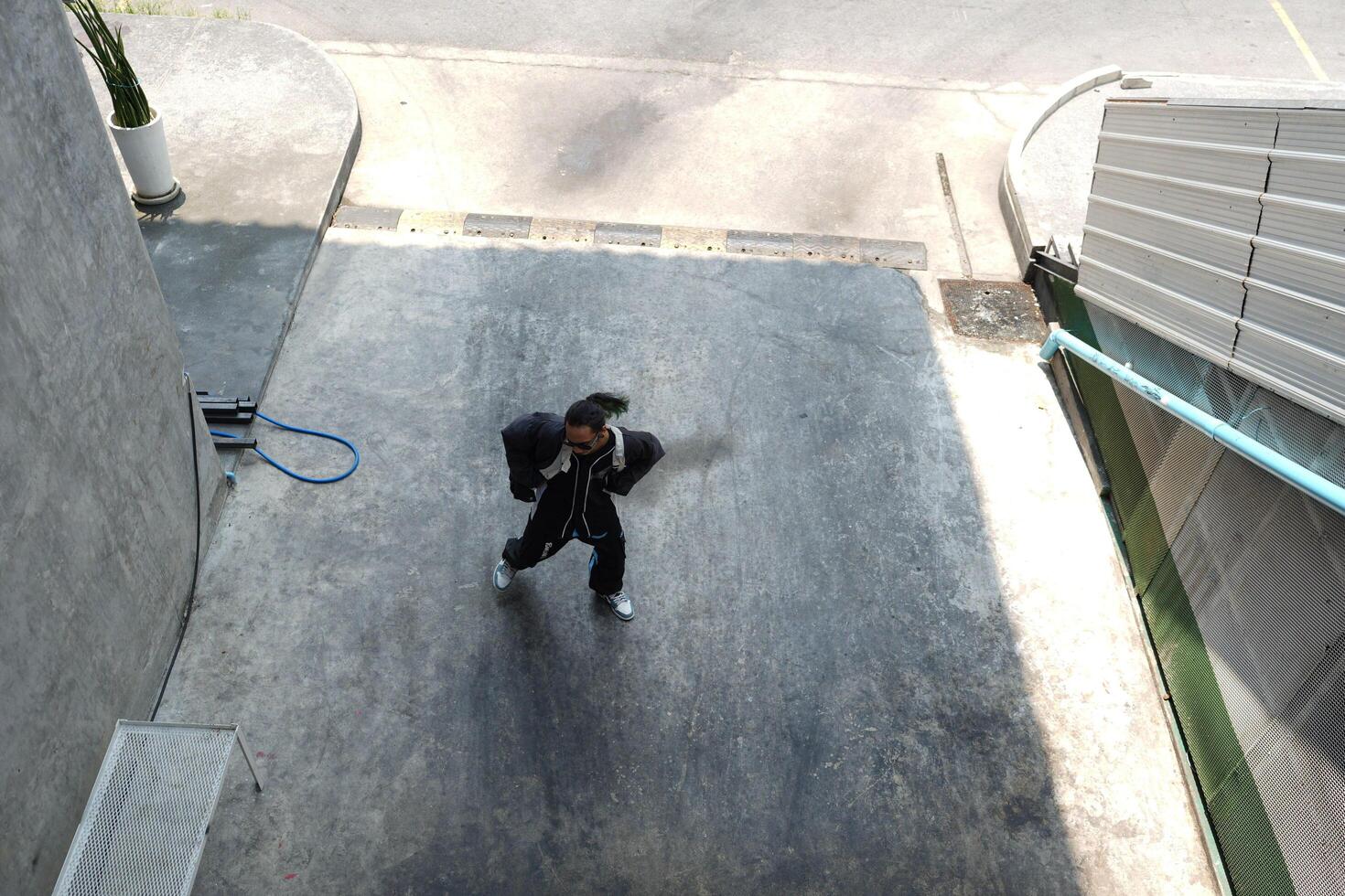 ASian man is dancing in hip hop style at outdoor space. Professional solo dancer is performing in public area. photo