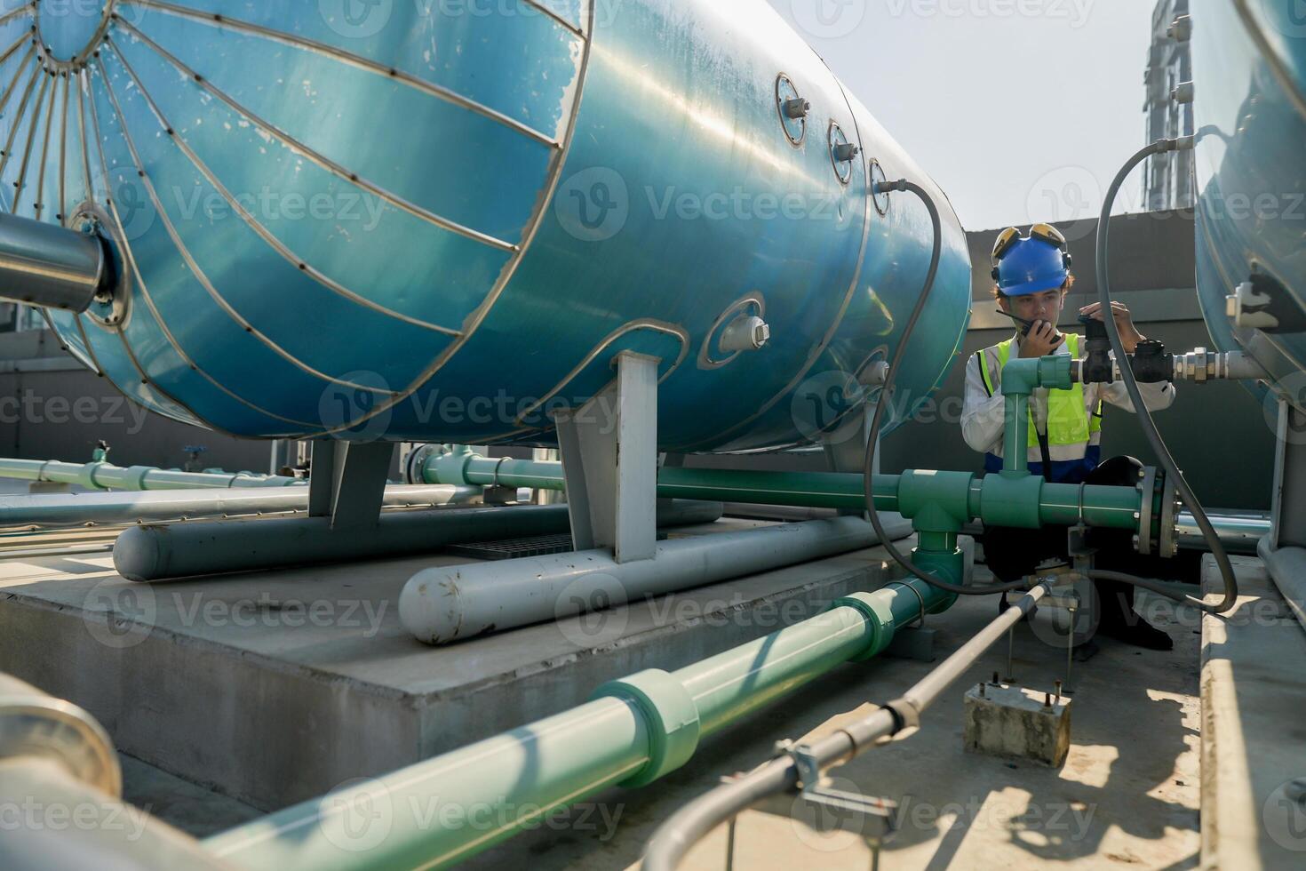 Urban rooftop scene showing a young engineer with a radio, inspecting and adjusting equipment in a sunny city environment. Safety and precision at work. photo