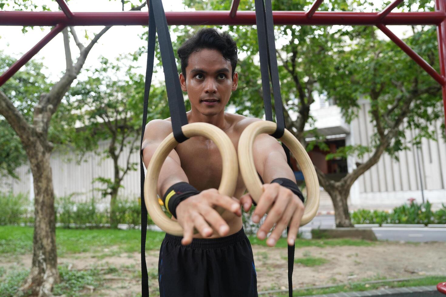 Asian man practicing gymnastics, doing gymnastics bar and hoop exercises and stretching, resting for sports. photo