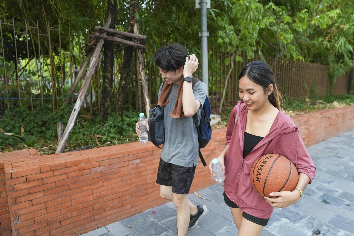 The male and female basketball players practice using the ball in the park court diligently and happily. photo