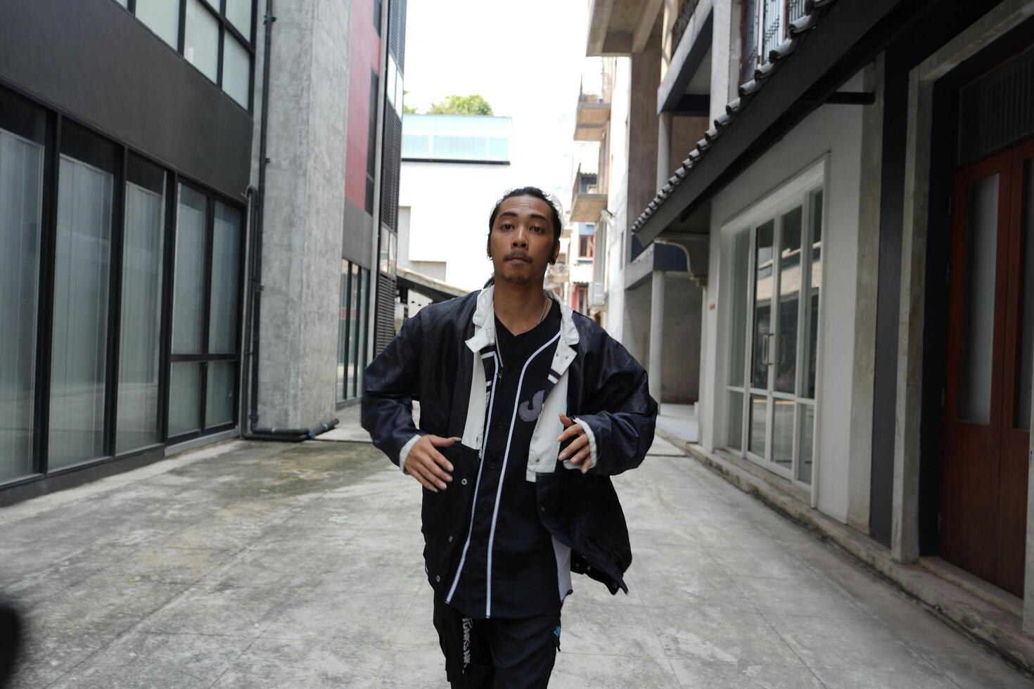 ASian man is dancing in hip hop style at outdoor space. Professional solo dancer is performing in public area. photo