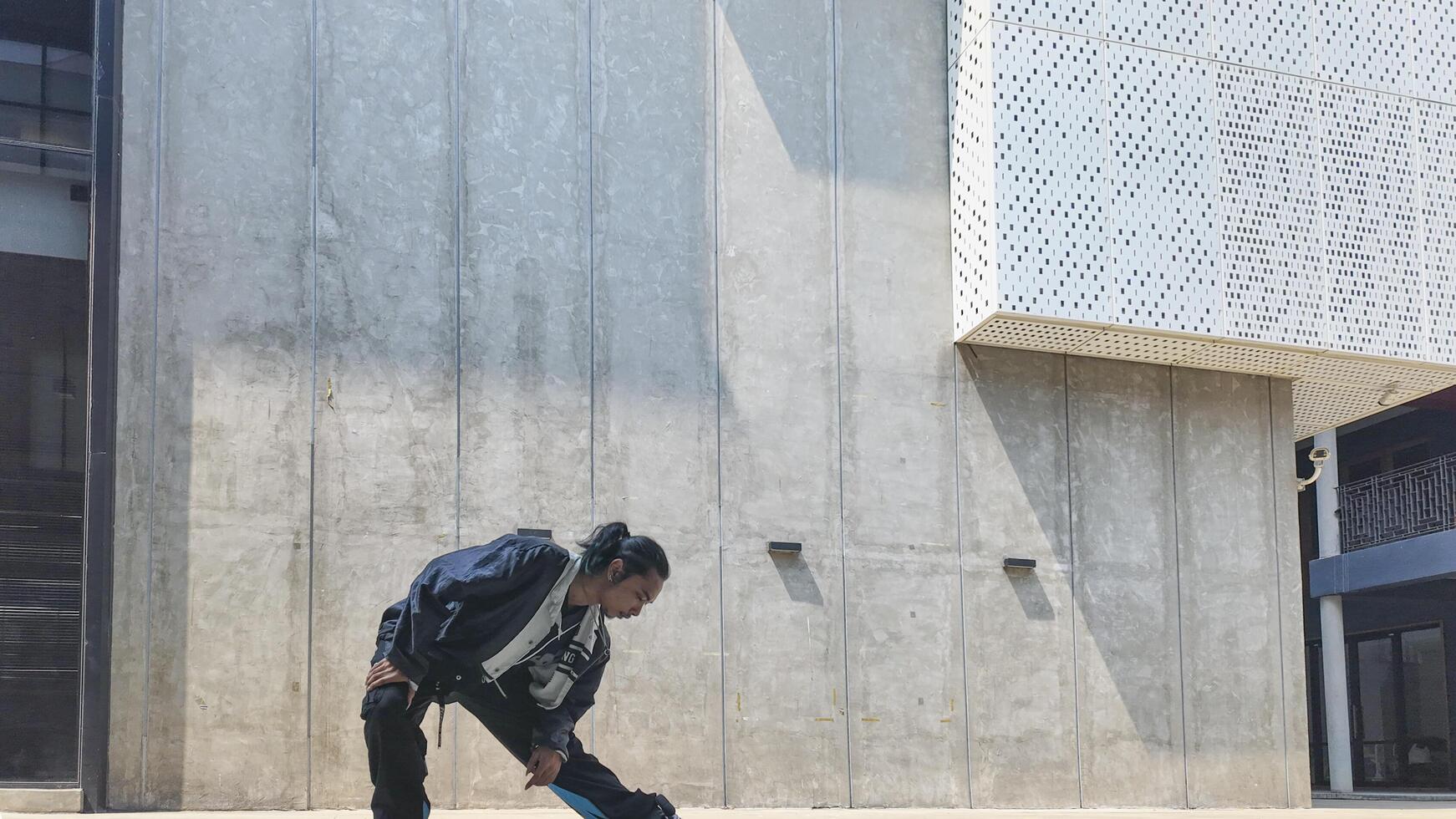 ASian man is dancing in hip hop style at outdoor space. Professional solo dancer is performing in public area. photo