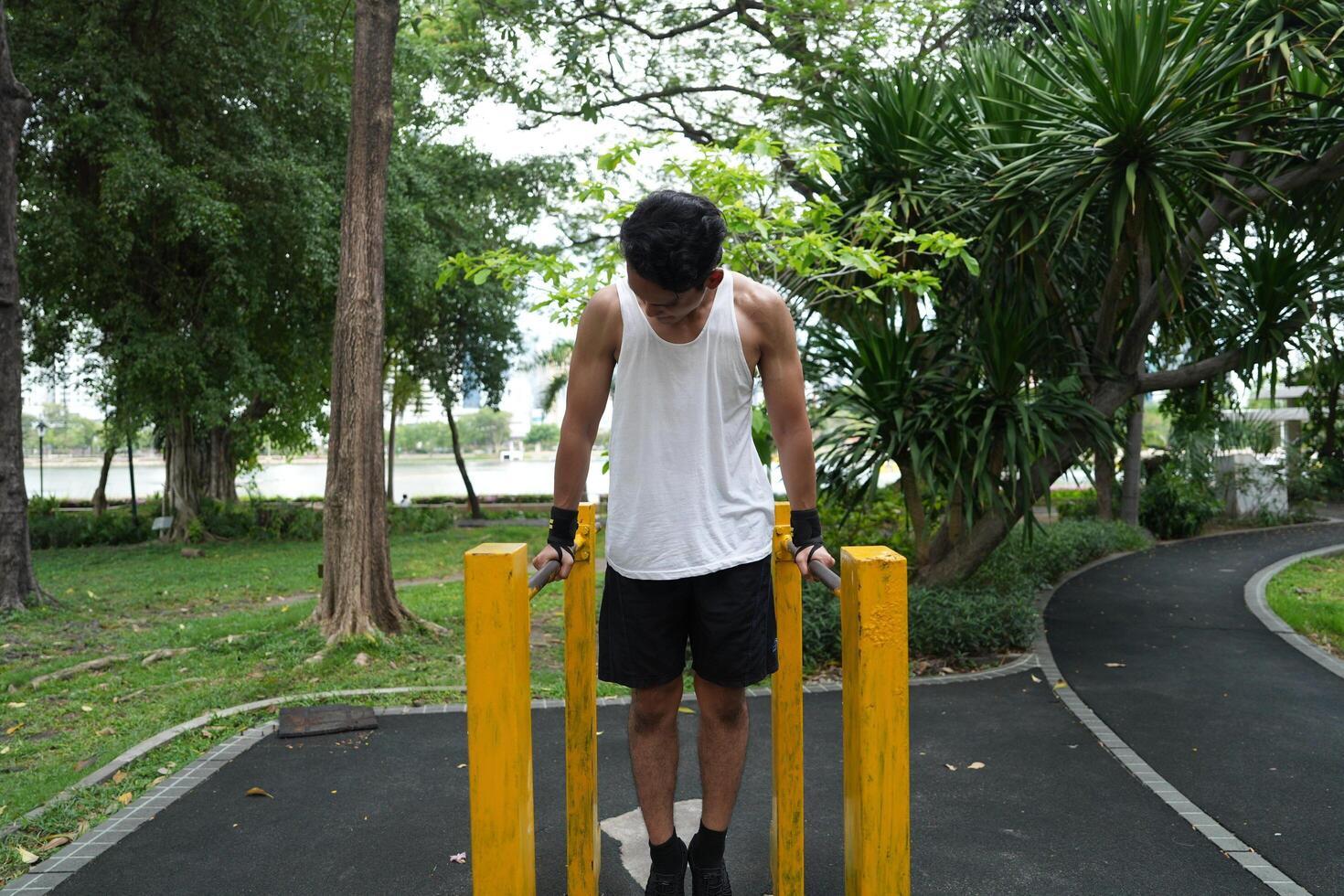 Asian man practicing gymnastics, doing gymnastics bar and hoop exercises and stretching, resting for sports. photo