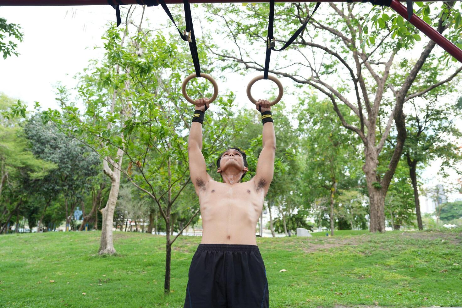 Asian man practicing gymnastics, doing gymnastics bar and hoop exercises and stretching, resting for sports. photo