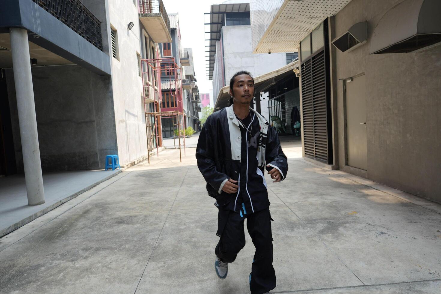 ASian man is dancing in hip hop style at outdoor space. Professional solo dancer is performing in public area. photo