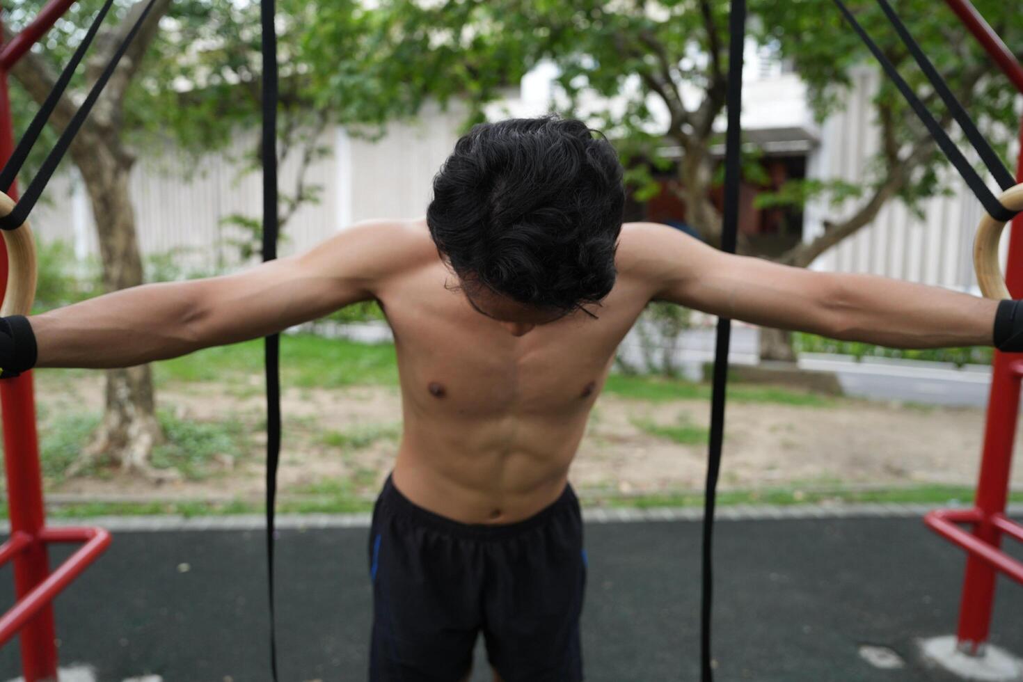 Asian man practicing gymnastics, doing gymnastics bar and hoop exercises and stretching, resting for sports. photo