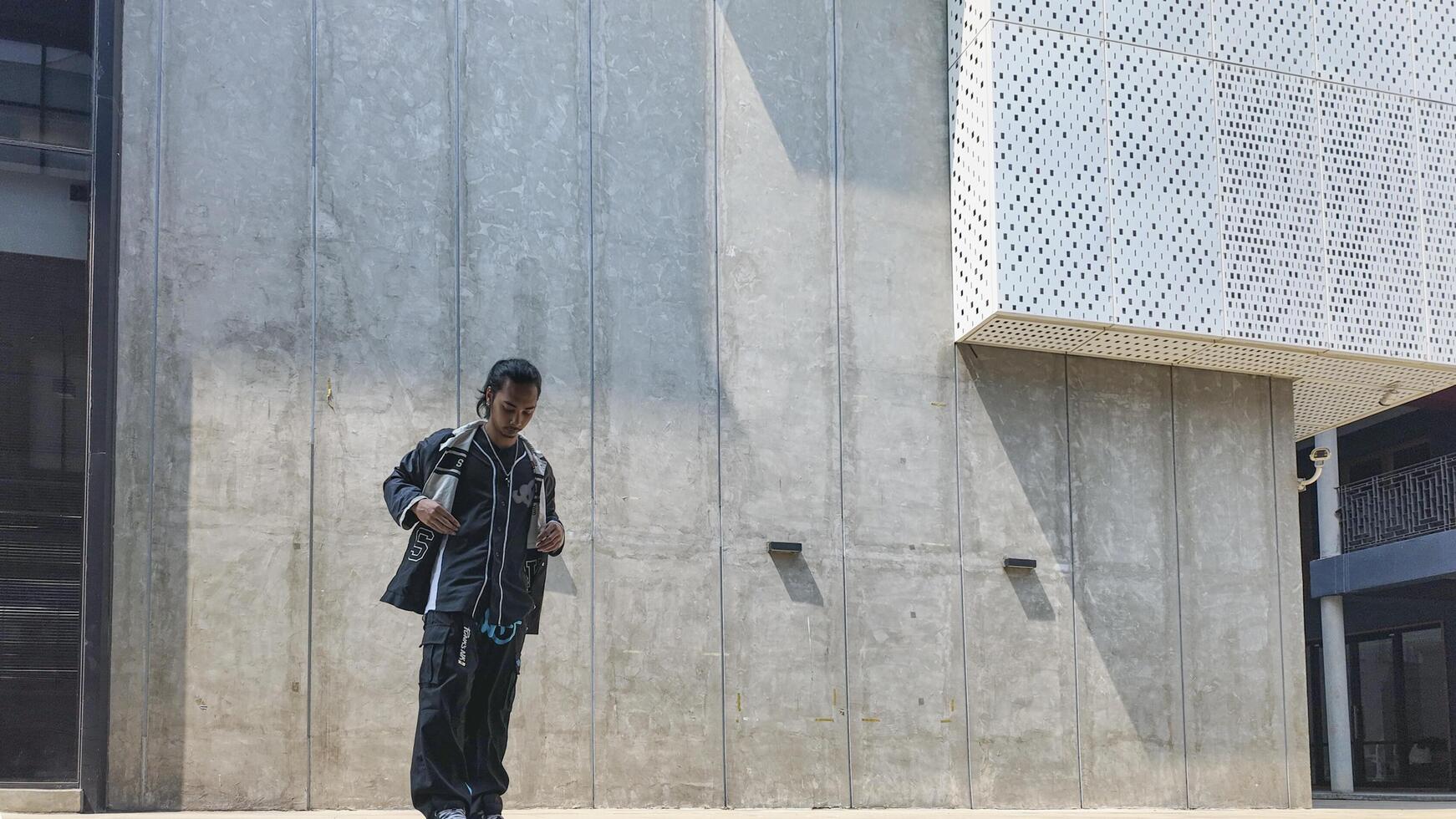 ASian man is dancing in hip hop style at outdoor space. Professional solo dancer is performing in public area. photo