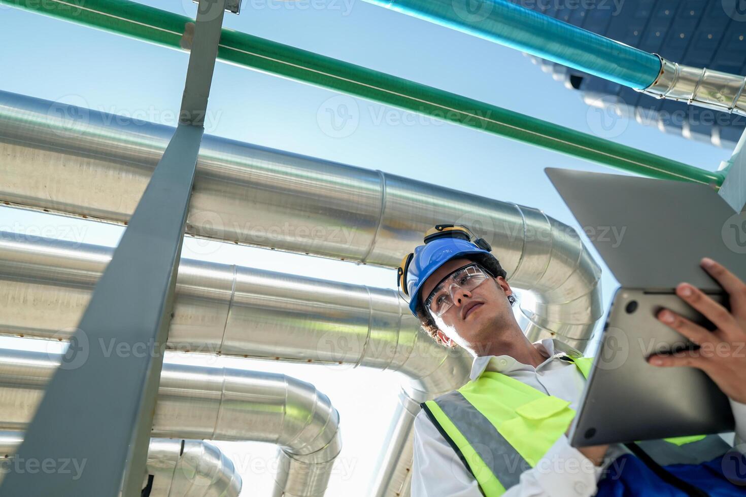 Industrial engineer adjusting pipeline valve with radio communication on construction site. Engineer on urban construction site using radio to coordinate with team on a sunny industrial rooftop. photo