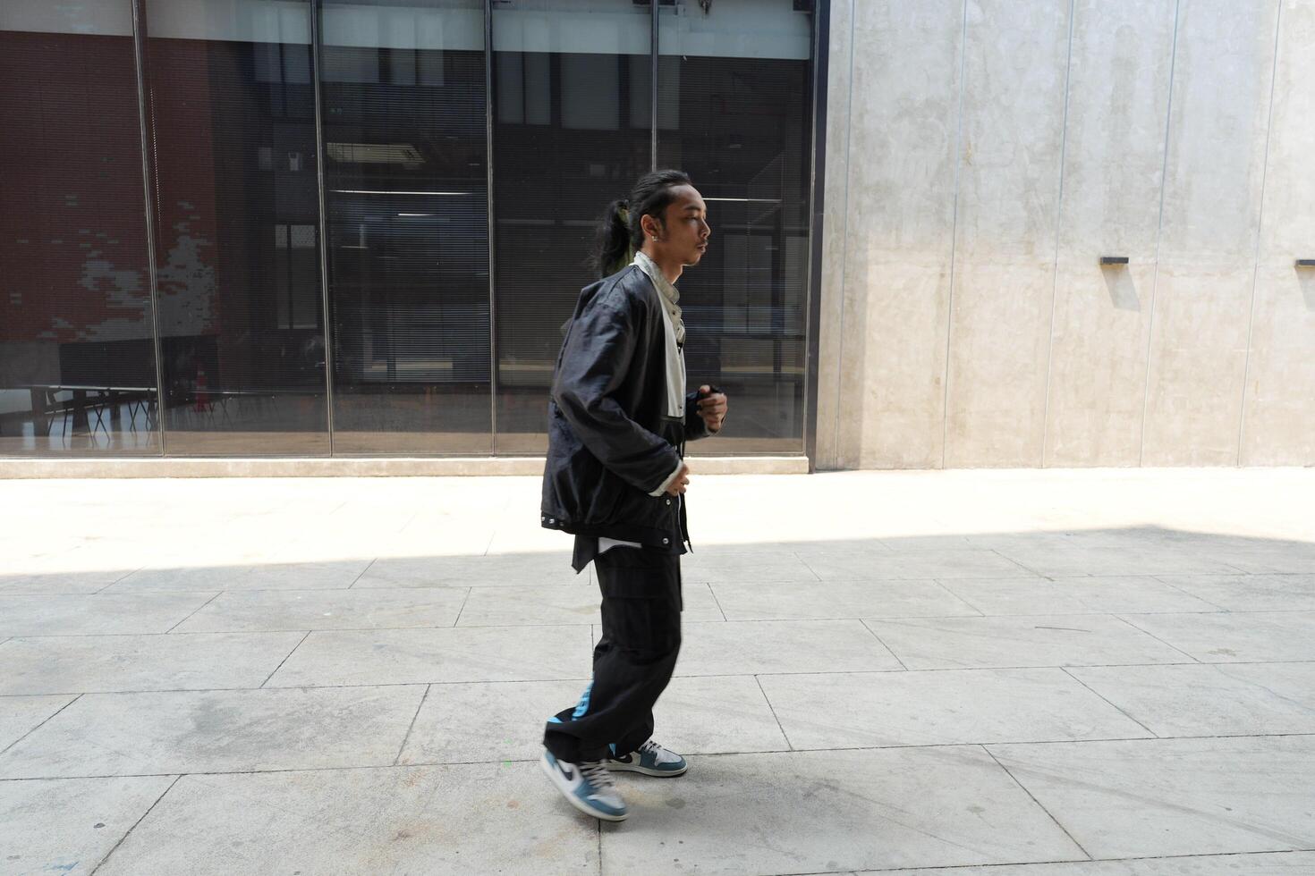 ASian man is dancing in hip hop style at outdoor space. Professional solo dancer is performing in public area. photo
