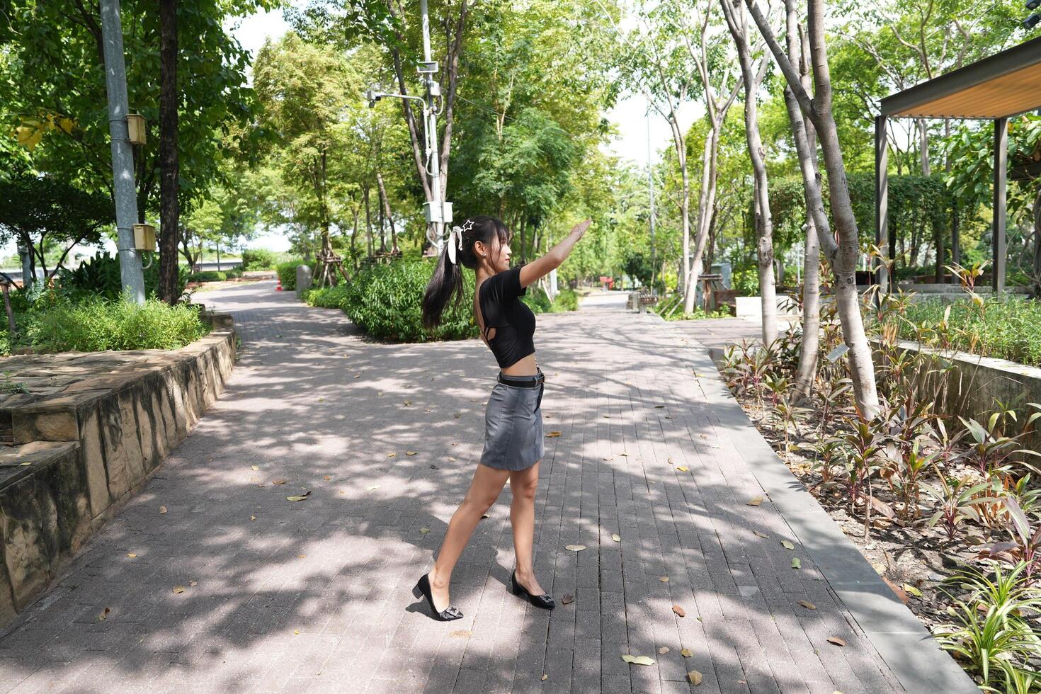 Asian woman dancing in the middle of a park photo