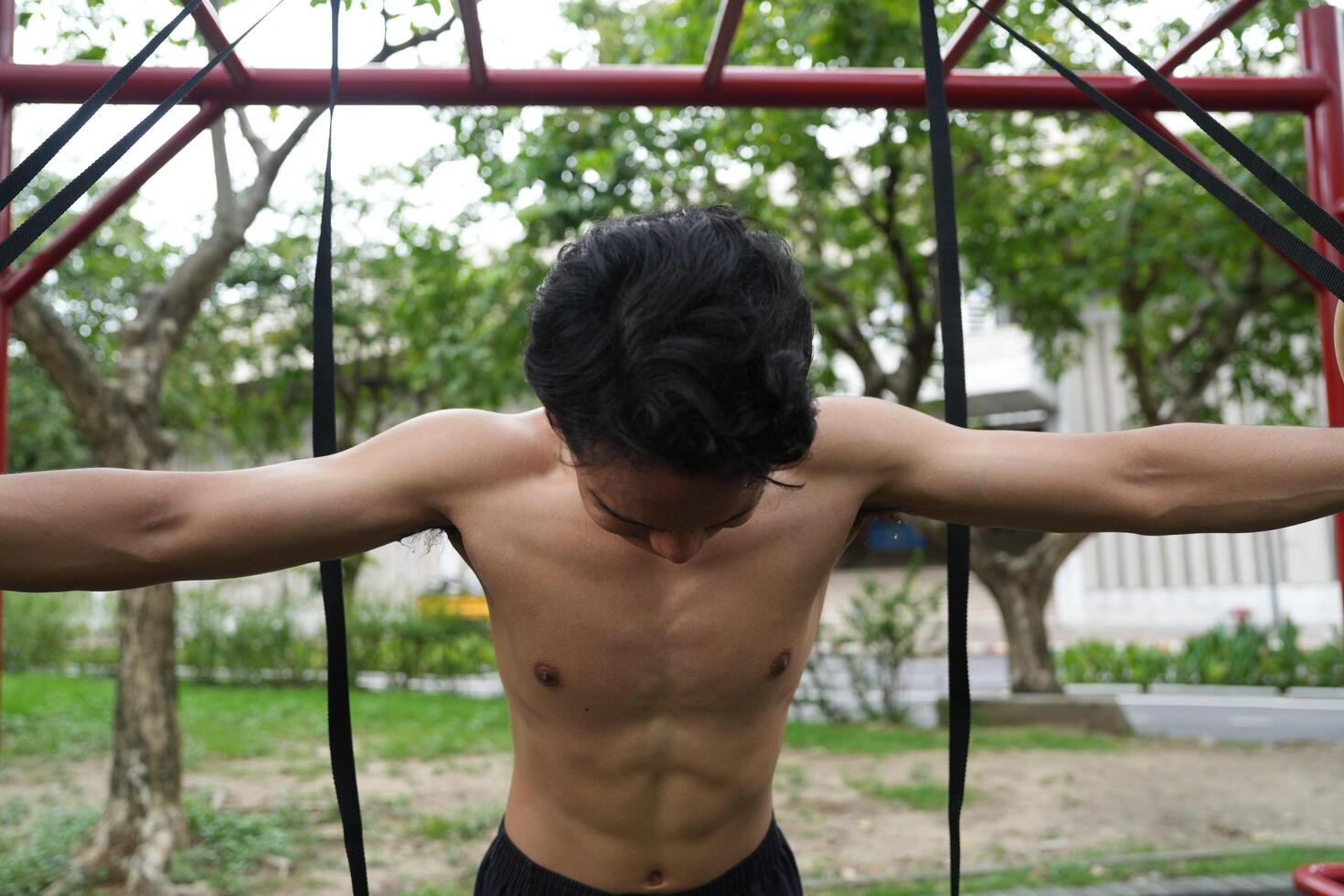 Asian man practicing gymnastics, doing gymnastics bar and hoop exercises and stretching, resting for sports. photo