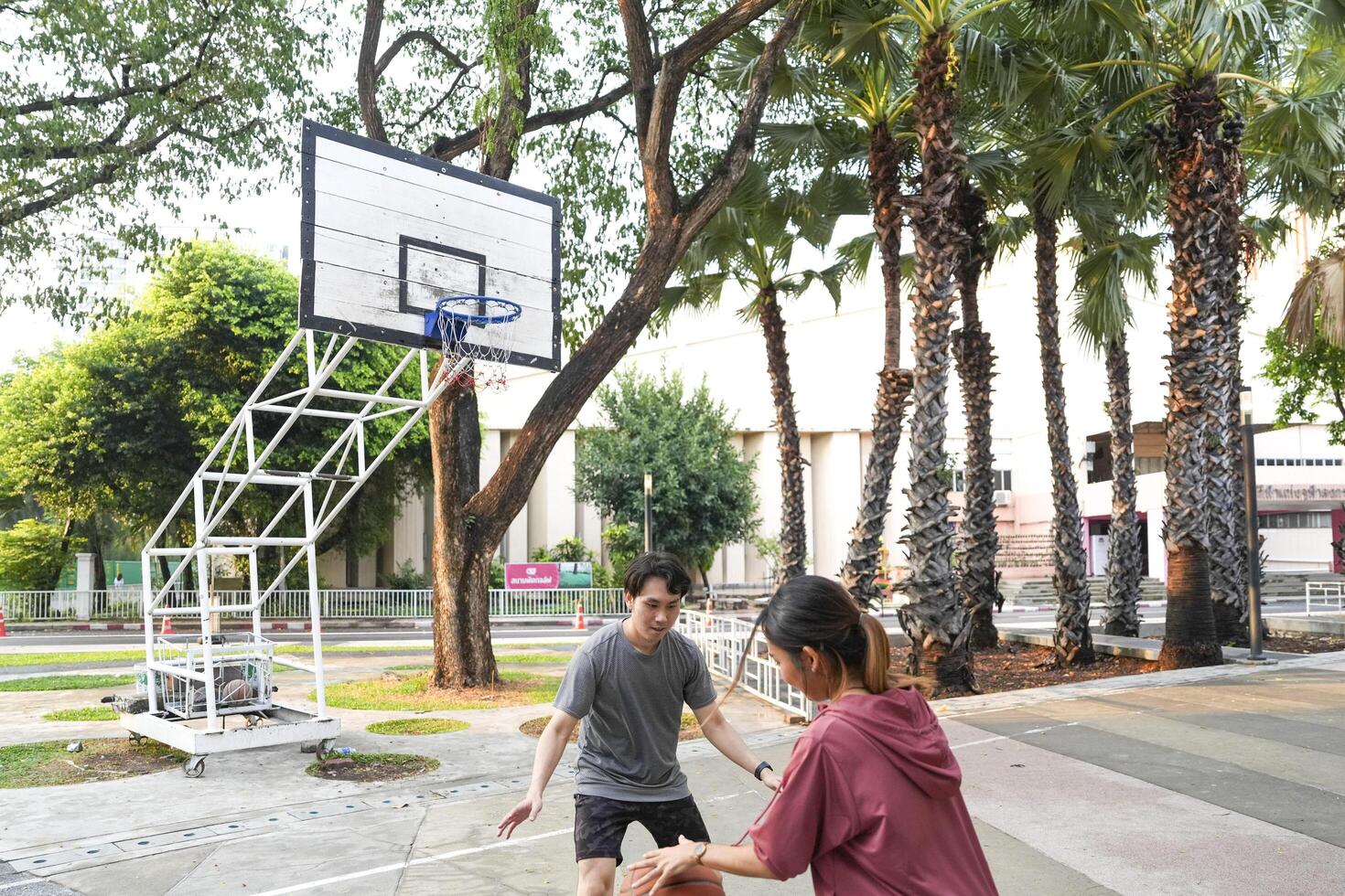 The male and female basketball players practice using the ball in the park court diligently and happily. photo